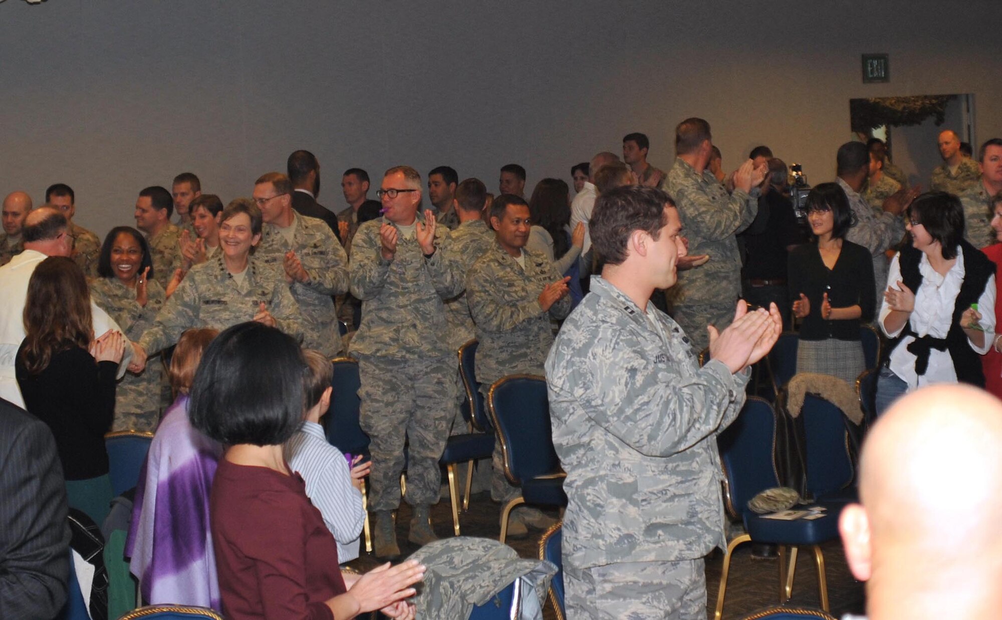 The audience jumps to its feet and claps with the arrival of the official party and airmen who recently returned from deployments at a Welcome Home Airmen ceremony held at Los Angeles AFB, Jan. 24.  (Photo by Sarah Corrice)
