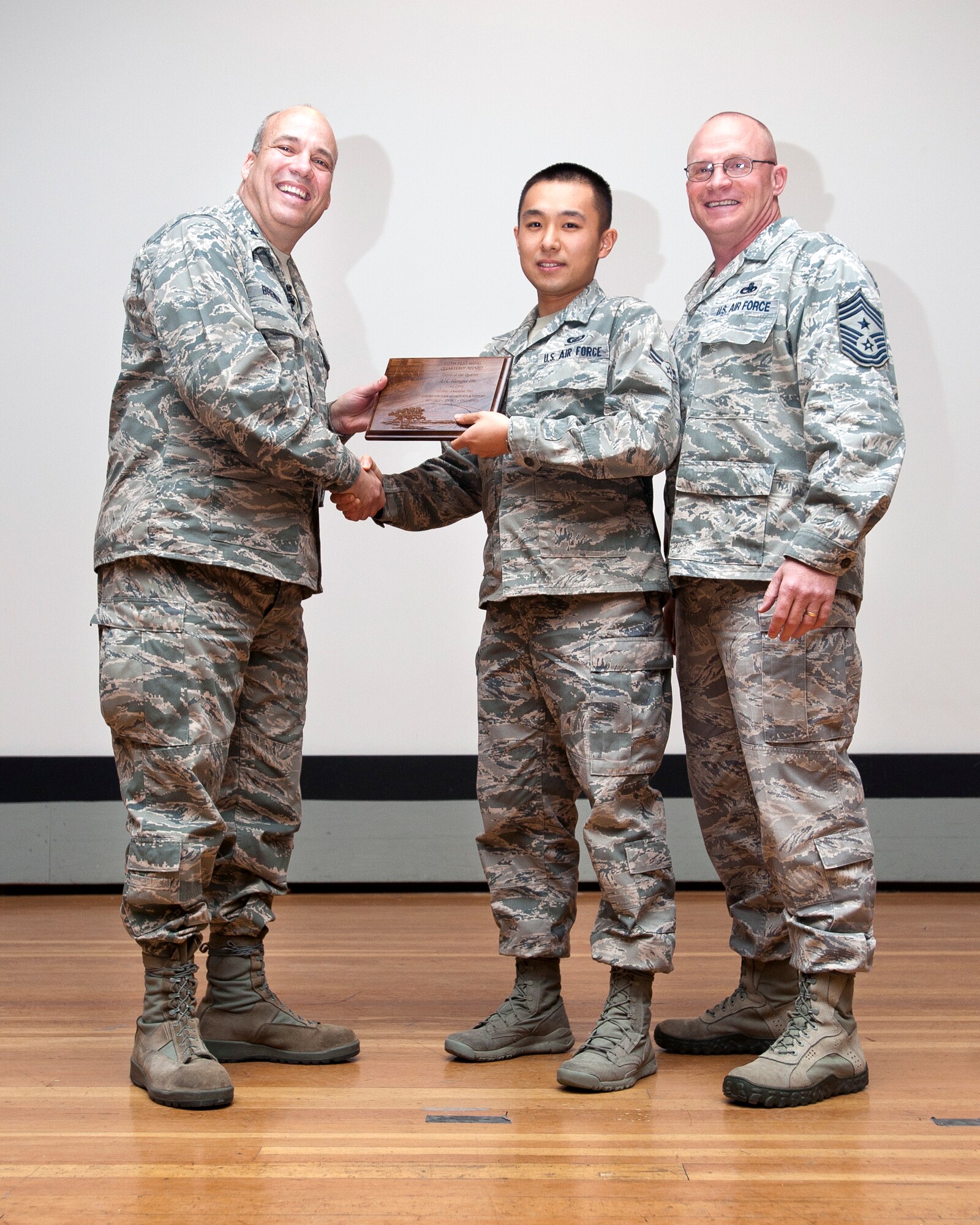 Airman 1st Class Hengui He, Wing Staff Agency (center) is presented his fourth quarter awards for Dorm Room of the Quarter by Brig. Gen. Michael T. Brewer (left) and Command Chief Master Sgt. Brian Randolph during the 412th Test Wing quarterly awards ceremony Jan. 24 in the Base Theater.  Awards were presented in 13 categories along with six Team Edwards members being presented with 30 year government service pins.  (U.S. Air Force photo by Ethan Wagner)