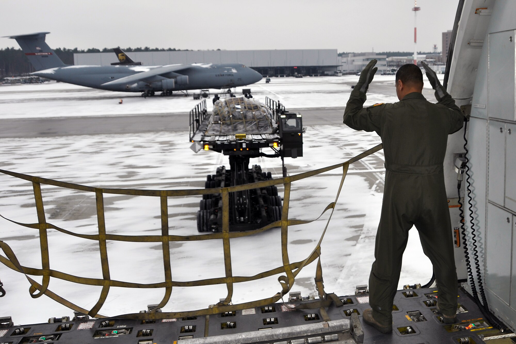 Master Sgt. Robert Rodriguez, 78th Air Refueling Squadon, guides incoming cargo toward a KC-10 Extender aircraft. Although the KC-l0's primary mission is aerial refueling, it can combine the tasks of a tanker and cargo aircraft by refueling fighters and simultaneously transporting the fighter support personnel and equipment. The KC-10 is also capable of transporting litter and ambulatory patients using patient support pallets during aeromedical evacuations. (U.S. Air Force photo by Col. Michael Underkofler)

