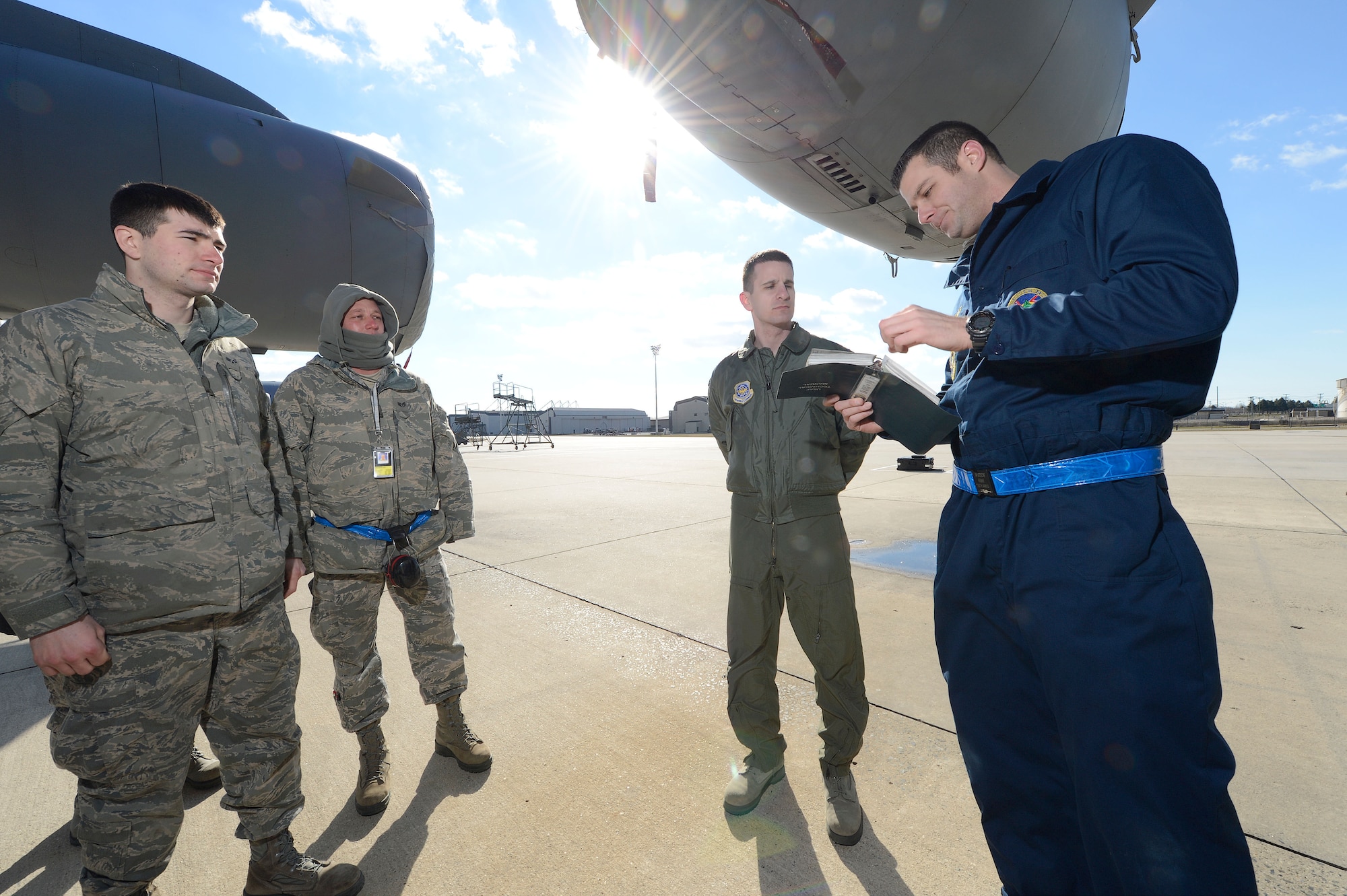 Tech. Sgt. William Goede, (right) 736th Aircraft Maintenance Squadron dedicated crew chief, reviews a technical order while standing underneath the left wing of a C-17A Globemaster III at Dover Air Force Base, Del. on Jan. 18, 2013. Goede is flanked by 1st Lt. Zack Jaeger, 3rd Airlift Squadron training officer. Jaeger and Goede participated in an operational maintenance immersion program to help aircrew and crew chiefs understand each other's roles and responsibilities. Additional aircraft maintenance specialists, Senior Airman Aaron Crompton and Staff Sgt. Steven Weaver, also listen to the discussion. This image has been digitally altered to remove sensitive information contained on an identification badge. U.S.Air Force photo/Greg L. Davis