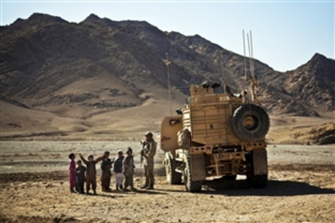 Afghan children crowd around a coalition force member maintaining security at an Afghan police compound in Farah province, Afghanistan, Jan. 24, 2013.