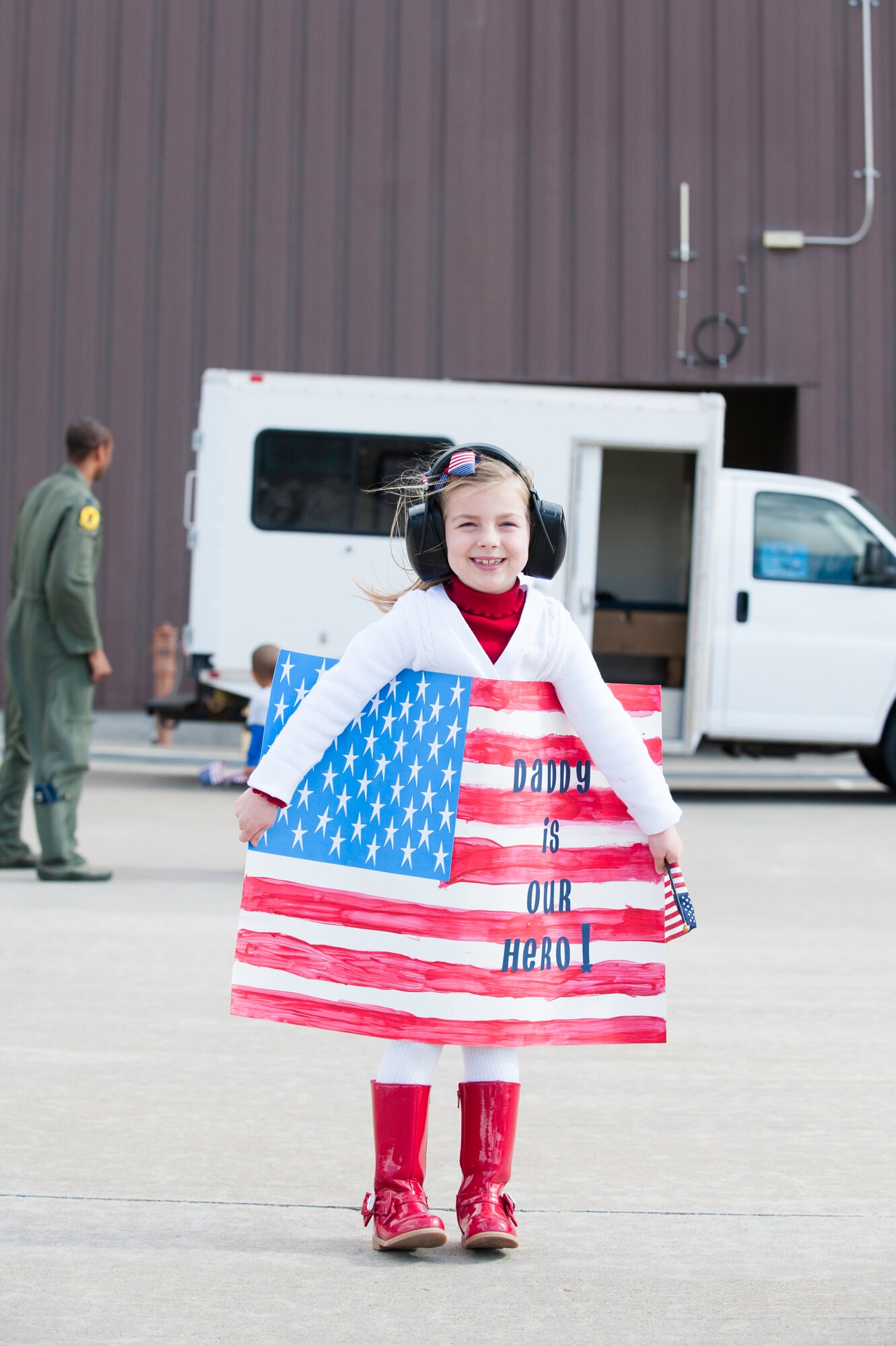 A child holds a sign for her father and awaits the arrival of F-22 Raptors on the Holloman AFB, N.M., flightline Jan. 28.  The aircraft and around 200 personnel returned Monday from a 9-month deployment to Southwest Asia ensuring regional security and joint tactical air operations.  (U.S. Air Force photo by 1st Lt. Stephanie Schonberger/Released)