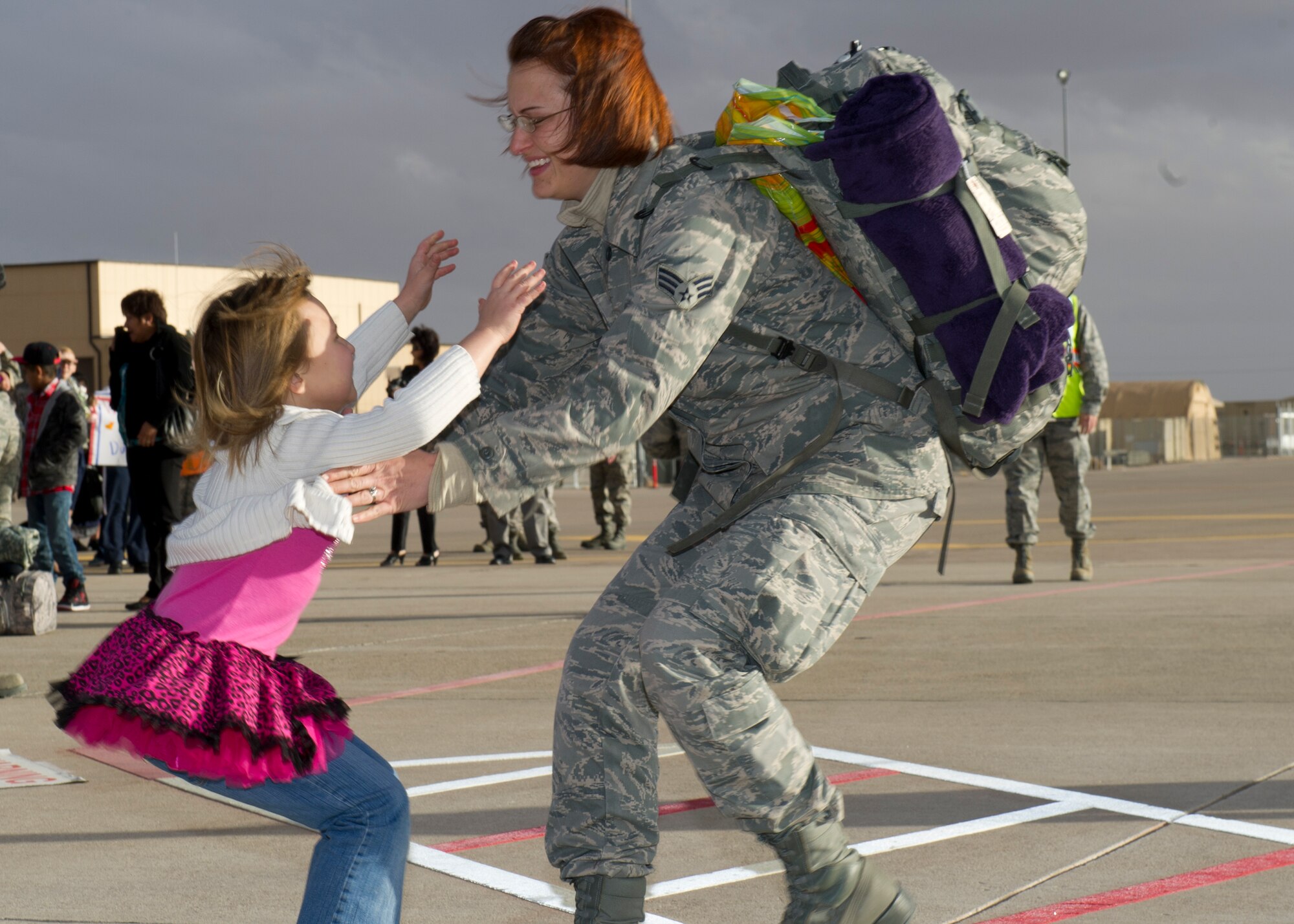 A Senior Airman returning from deployment greets her daughter after landing on the Holloman AFB, N.M., flightline Jan. 28.  F-22 Raptors and around 200 personnel returned Monday from a 9-month deployment to Southwest Asia ensuring regional security and joint tactical air operations. (U.S. Air Force photo by Airman 1st Class Michael Shoemaker/Released)