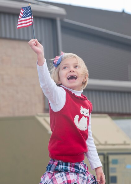 A daughter of one of the returning 7th Fighter Squadron pilots waves a flag while she waits to be reunited with her father on the Holloman AFB, N.M., flightline Jan. 28.  The aircraft and around 200 personnel returned Monday from a 9-month deployment to Southwest Asia ensuring regional security and joint tactical air operations. (U.S. Air Force photo by Airman 1st Class Leah Murray/Released)