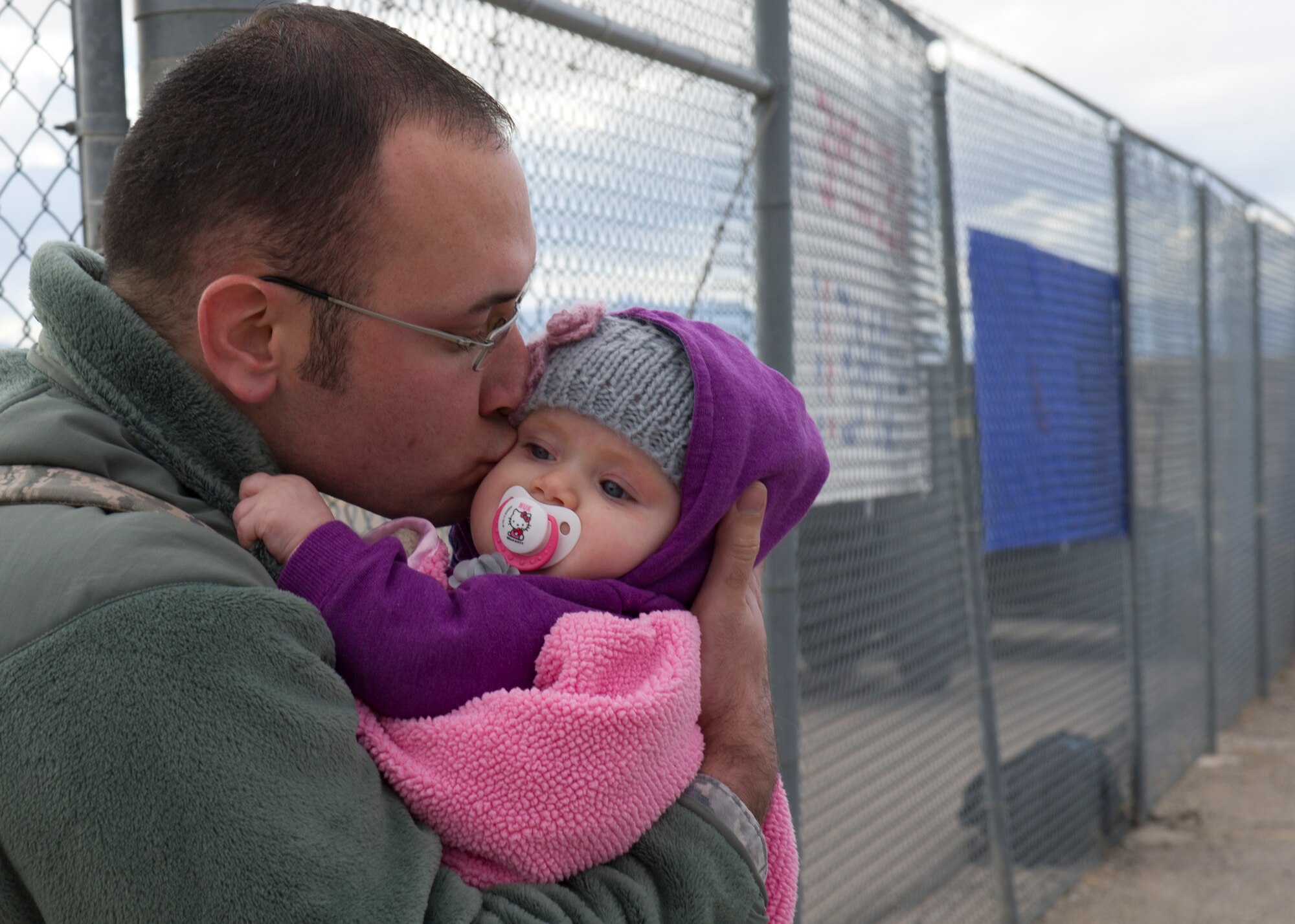 An Airman returning from deployment reunites with his family on the Holloman Air Force Base, N.M. flightline, Jan 28. F-22 Raptors and around 200 personnel returned Monday from a 9-month deployment to Southwest Asia ensuring regional security and joint tactical air operations. (U.S. Air Force photo by Airman 1st Class Michael Shoemaker/Released)