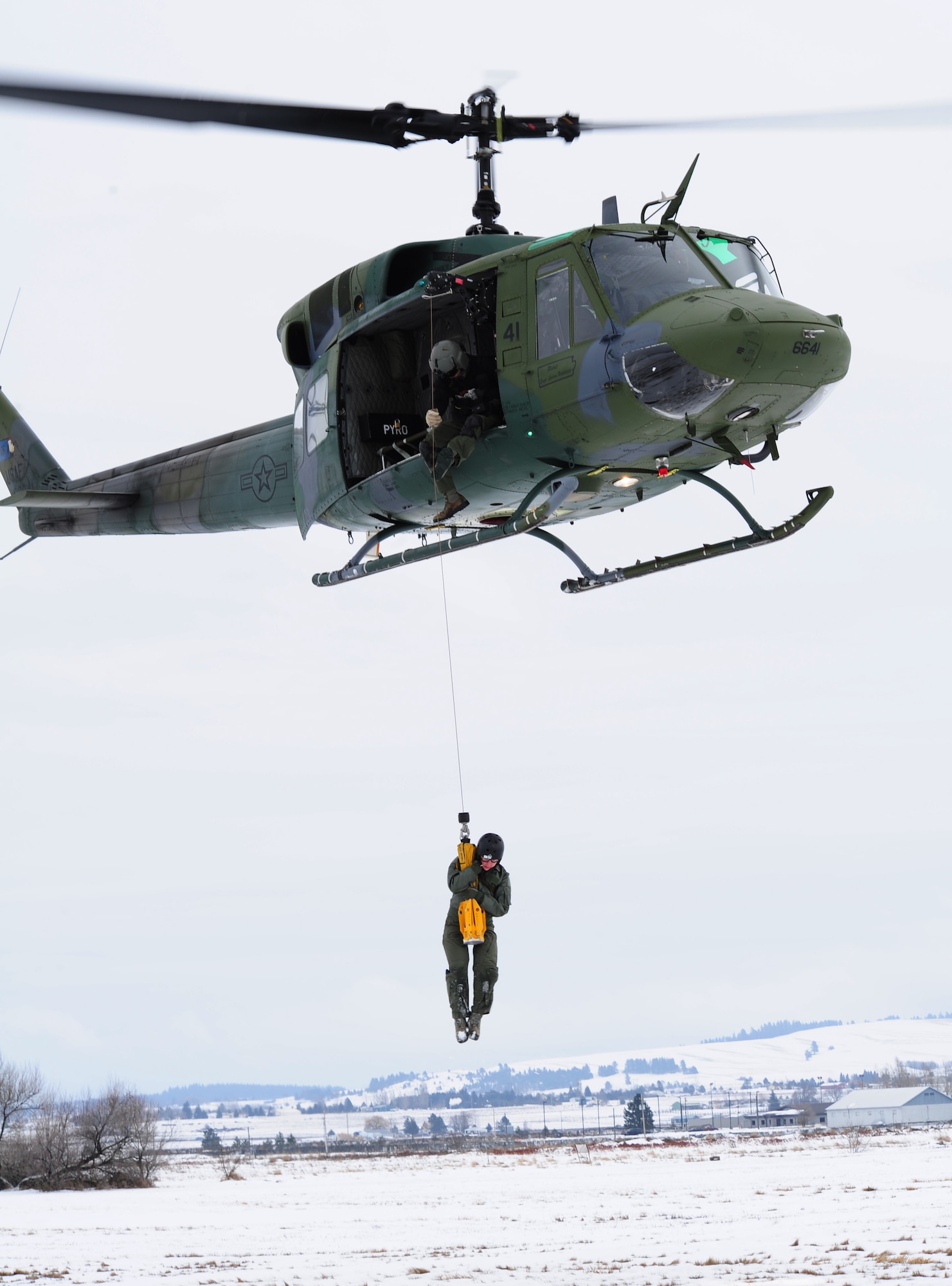 A survival school student is hoisted into a UH-1N Iroquois helicopter during a training exercise at the survival, evasion, resistance and escape school at Fairchild Air Force Base, Wash., Jan. 25, 2013. The school provides courses to prepare students on how to successfully parachute, land, survive and get recovered using the devices that the instructors taught them to use. (U.S. Air Force photo by Airman 1st Class Janelle Patiño)