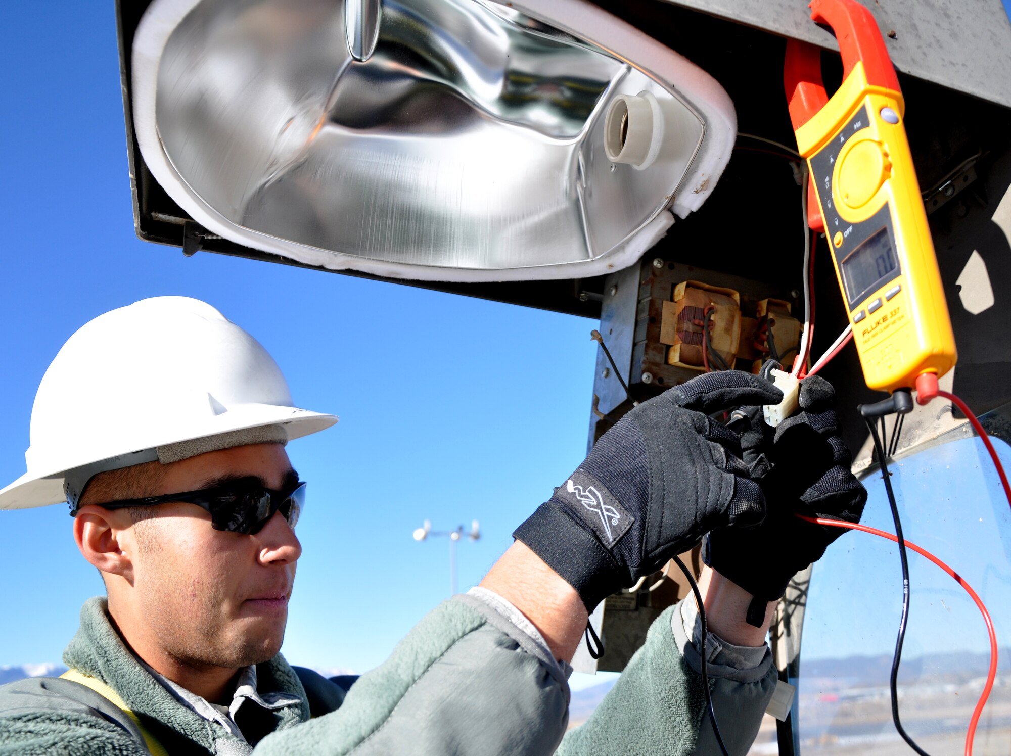 PETERSON AIR FORCE BASE, Colo. -- Airman 1st Class Jerry Harrison, 21st Civil Engineer Squadron electrical systems journeyman, tests the incoming wire to a street lamp Jan. 4, 2012, at a parking lot east of the softball fields. The 21st CES operates and sustains essential facilities and utility infrastructure systems on base, responding to myriad work orders daily including maintaining roads, generators, and water and electrical lines. (U.S. Air Force photo/Senior Airman Jacob Morgan)