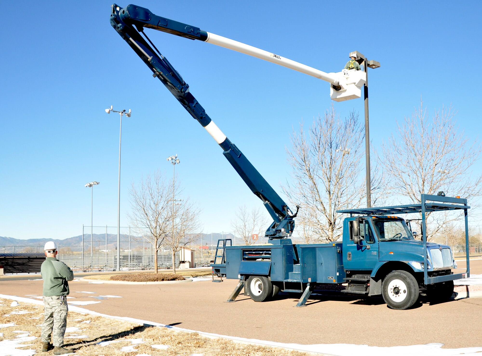 PETERSON AIR FORCE BASE, Colo. -- Two electrical systems technicians from the 21st Civil Engineer Squadron visit a parking lot east of the softball fields Jan. 4, 2012. The 21st CES operates and sustains essential facilities and utility infrastructure systems on base, responding to myriad work orders daily including maintaining roads, generators, and water and electrical lines. (U.S. Air Force photo/Senior Airman Jacob Morgan)