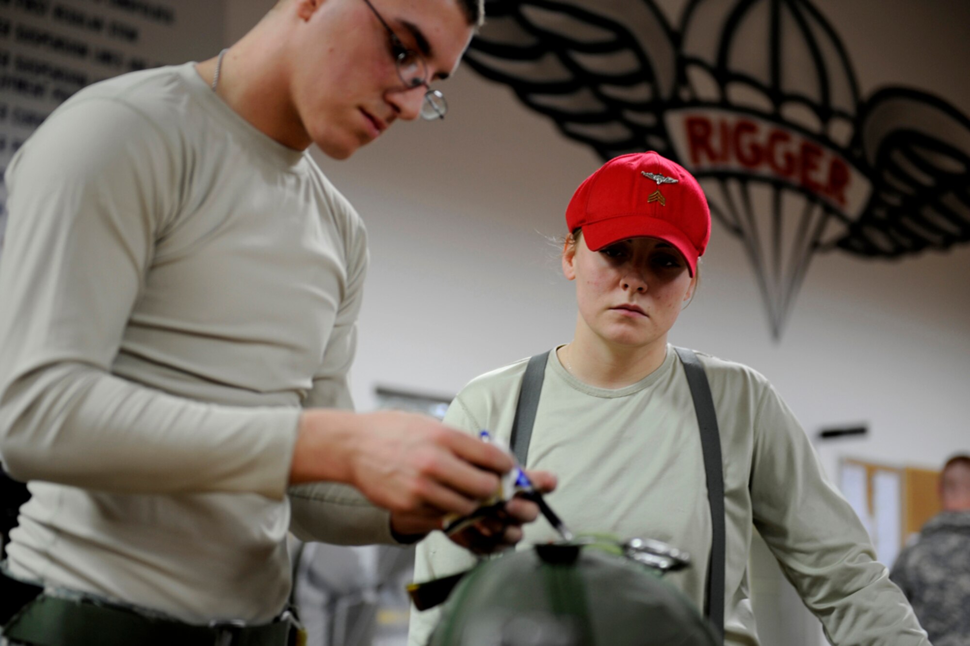 Army Sgt. Jerica Ogle, parachute packer inspector from the 4th Quartermaster Detachment, oversees Spc. David Fosbinder, parachute packer, while he packs a parachute on JBER, Jan. 15. Ogle and Frostbinder are both from the 4th Quartermaster Detachment. She ensures that all the parachute packers do not skip steps in the packing process. Each parachute packed is overseen to ensure its safety and reliability for the Army mission. Ogle is from Middleborough, Ky., and Fostbinder is from Nashville, Tenn.