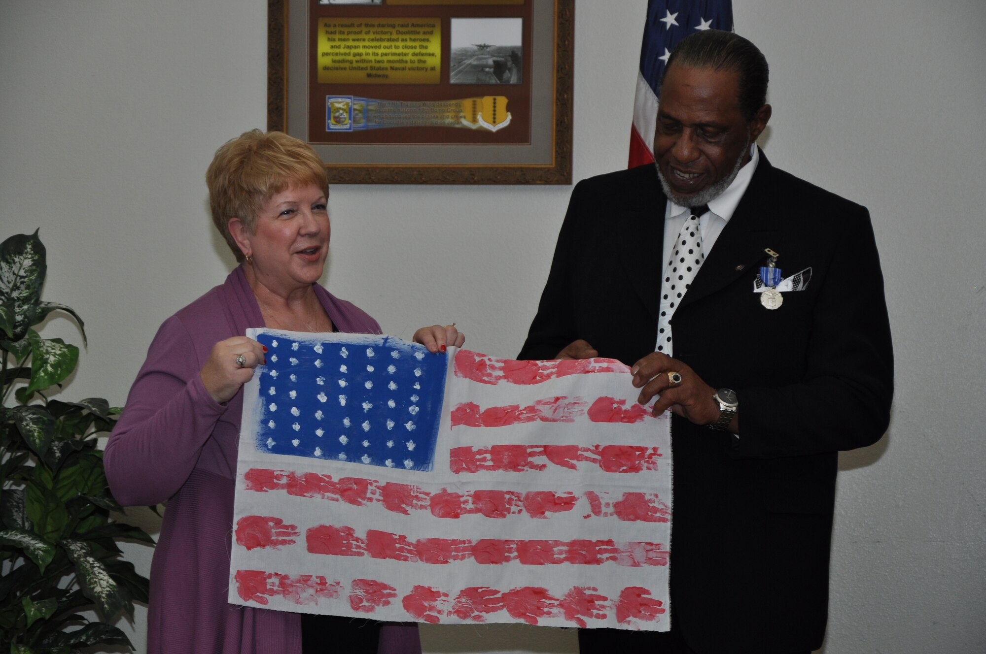GOODFELLOW AIR FORCE BASE, Texas – Marilyn Moore, Child Development Center assistant director, gives Anthony Hooks Jr., former Airman and Family Readiness Center flight chief, a flag made by the children of the CDC for his retirement ceremony at the Event Center, Jan. 25. The lines on the flag are made with the hand prints of the children from the CDC. (U.S. Air Force photo/ Airman 1st Class Joshua Edwards)