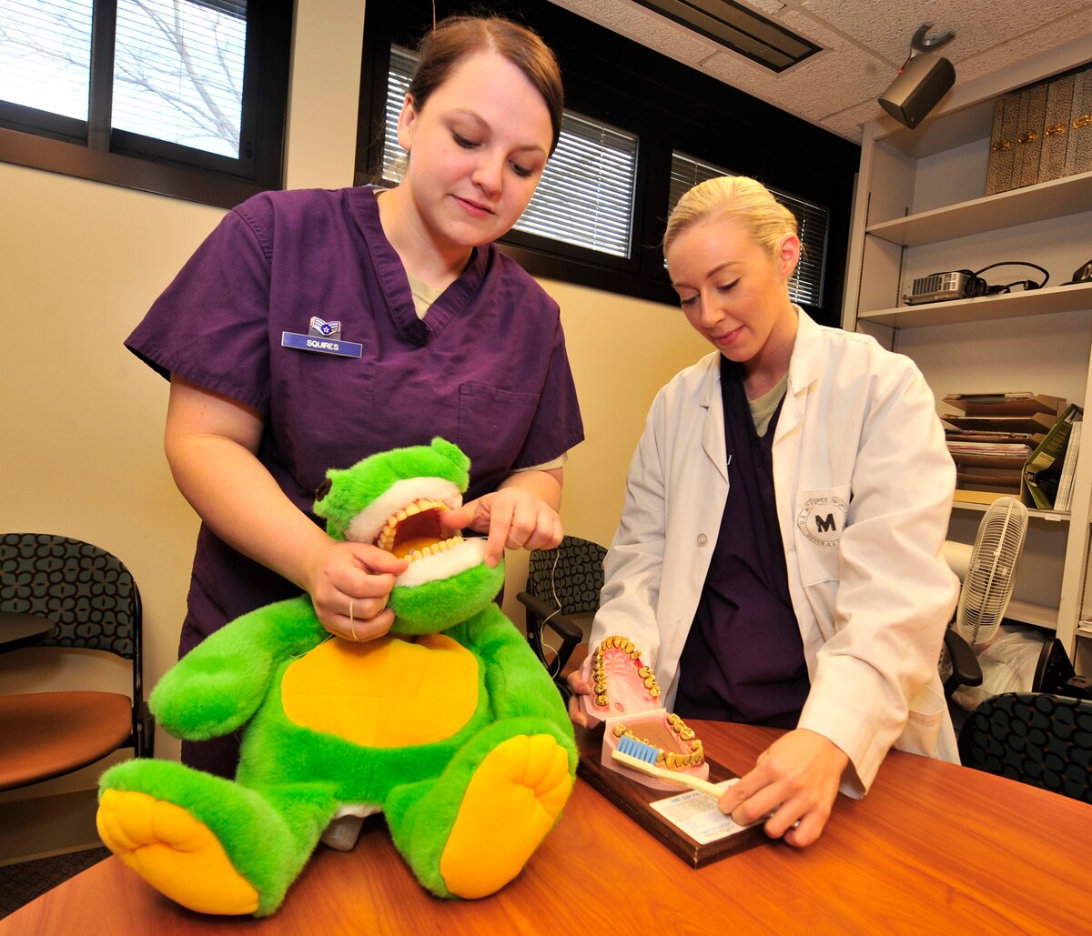 Senior Airman Laura Squires, 436th Dental Squadron dental technician, demonstrates how to floss on Dennis the Alligator, while Senior Airman Ashton Collins, 436th Dental Squadron dental technician, demonstrates how to brush your teeth on Mr. Yuck Mouth Jan. 24, 2013, at Dover Air Force Base, Del. Squires and Collins were practicing for Children’s Dental Health Month, when members of the 436th DS will travel to local schools to promote dental health to students. (U.S. Air Force photo by Tech. Sgt. Chuck Walker)