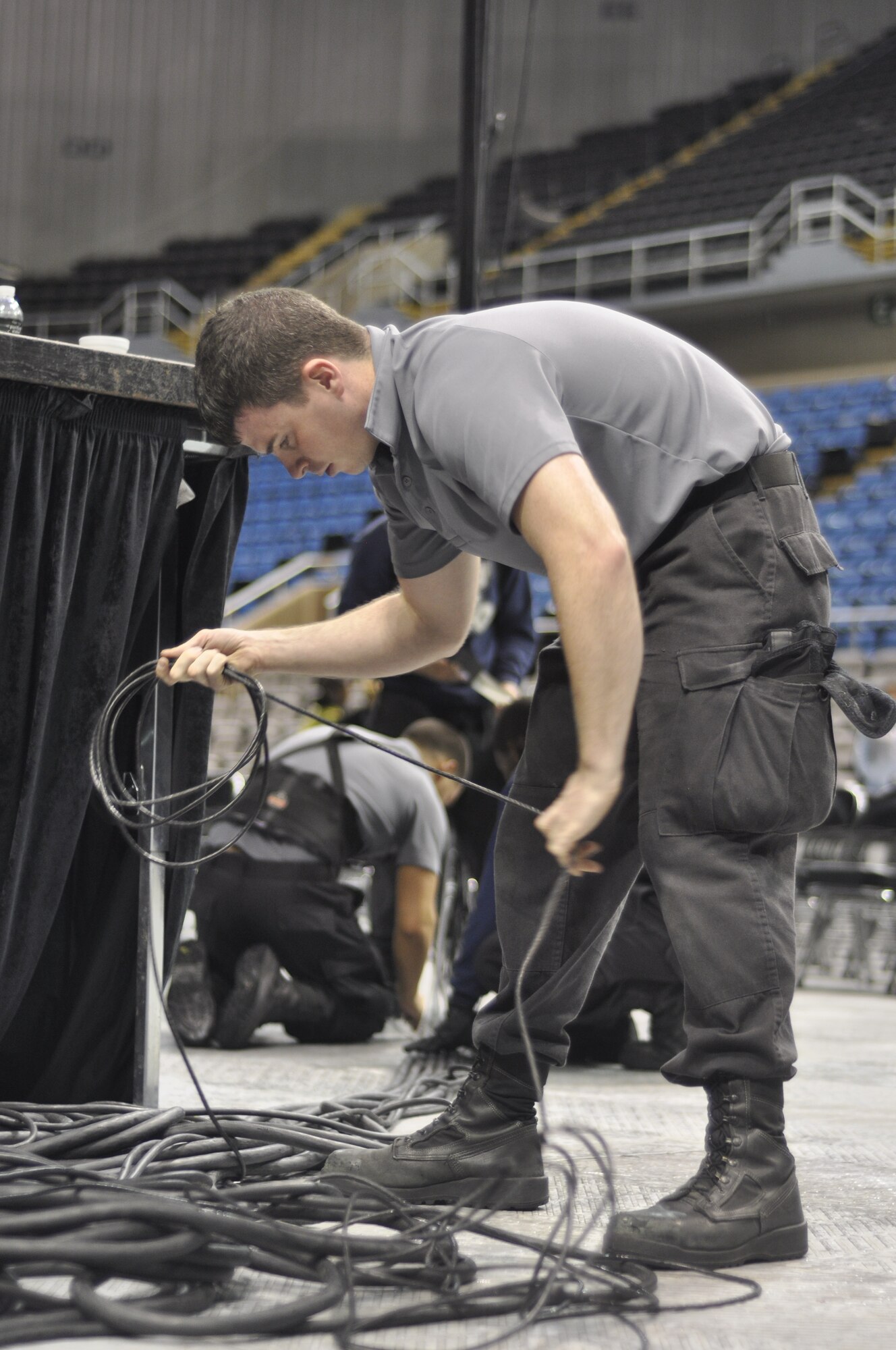 Senior Airman Roger Payne, Tops in Blue audio engineer, coils a wire while setting up for the team’s performance for Keesler Air Force Base Airmen and community members Jan. 27, 2013 at the Mississippi Coast Coliseum. The group is responsible for setting up more than 64,000 pounds of equipment before each show. This year’s tour takes the group to more than 20 countries with nearly 130 performances. For more information on the team or audition requirements, visit www.topsinblue.com.  (U.S. Air Force photo by 1st Lt. Victoria Porto) 