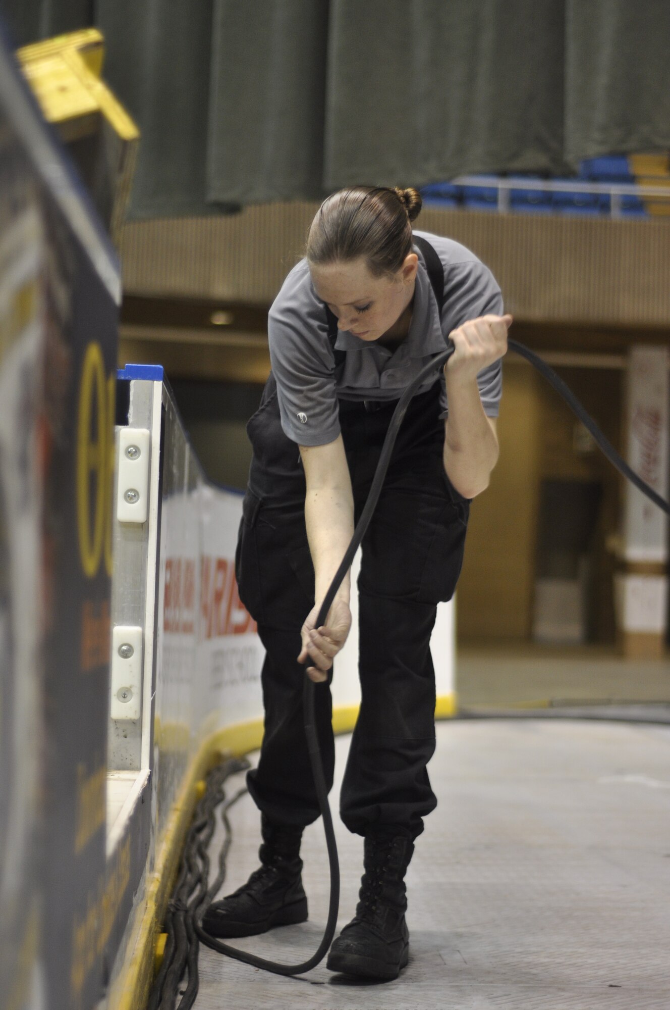 Senior Airman Ruth Bryce, Tops in Blue video director, lays down wire while setting up for the team’s performance for Keesler Air Force Base Airmen and community members Jan. 27, 2013 at the Mississippi Coast Coliseum. The 31 members of Tops in Blue are responsible for setting up and tearing down their stage, sound and light equipment for each show. (U.S. Air Force photo by 1st Lt. Victoria Porto)