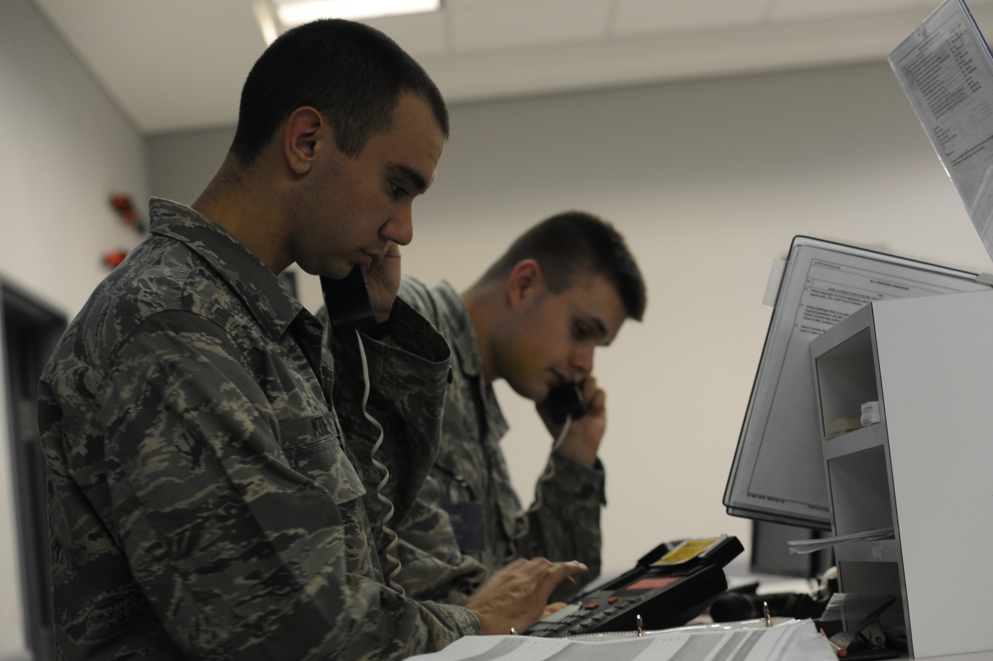 U.S. Air Force Airman 1st Class David Iles and Airman Basic Josh Moore, 733rd Air Mobility Squadron air transportation passenger service agents, update flight rosters on Kadena Air Base, Japan, Jan. 29, 2013. The Space Availability program includes the EML program, which gives service members and their families a higher priority level when they fly. (U.S. Air Force photo/Airman 1st Class Malia Jenkins)