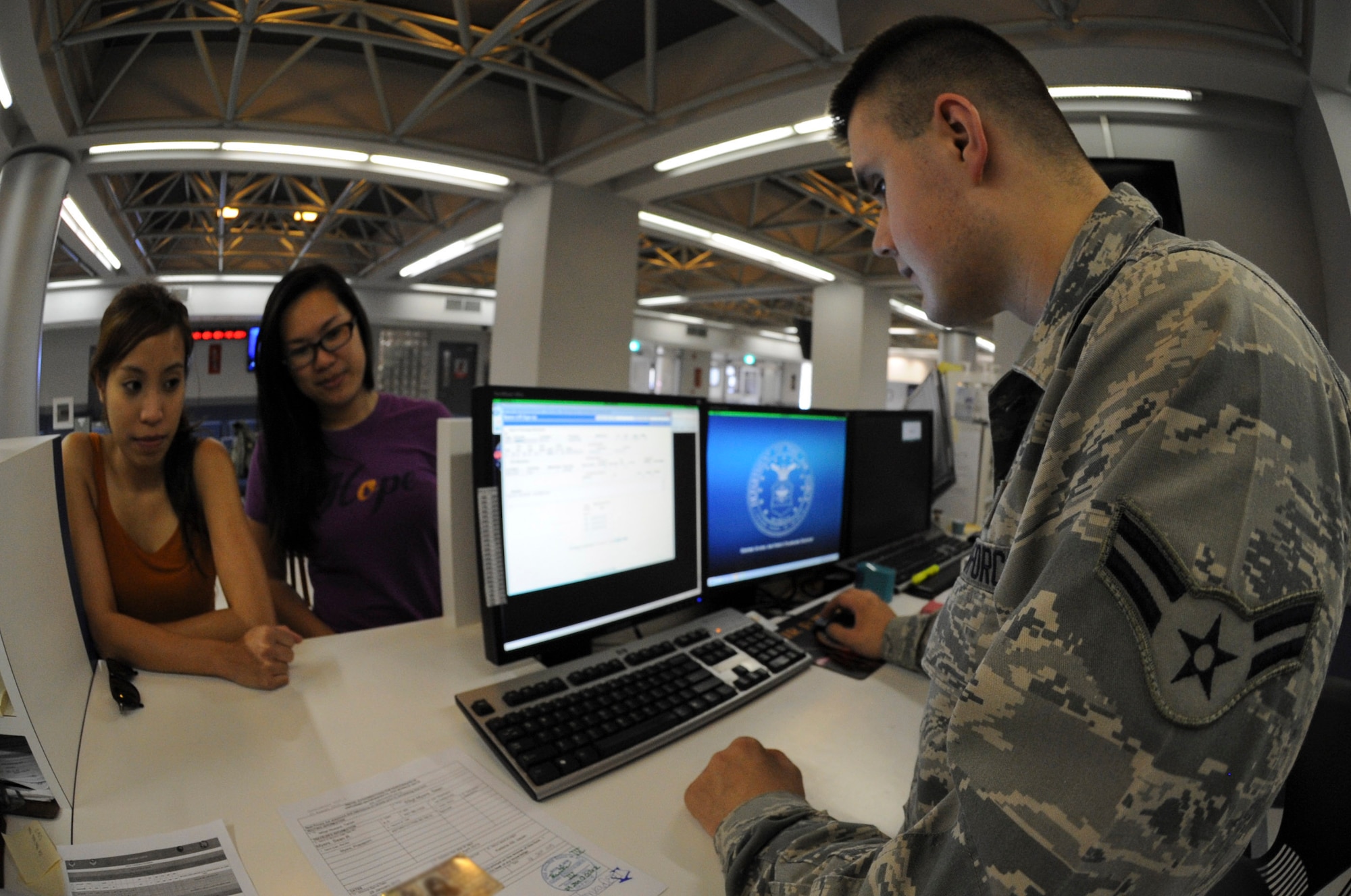 U.S. Air Force Airman 1st Class David Iles, 733rd Air Mobility Squadron air transportation passenger service agent, gives customers information on flights for the Space Availability program on Kadena Air Base, Japan, Jan. 29, 2013. The Environmental Morale and Leave program is a section of Space A which gives service members and their families a higher priority level when they fly. (U.S. Air Force photo/Airman 1st Class Malia Jenkins)