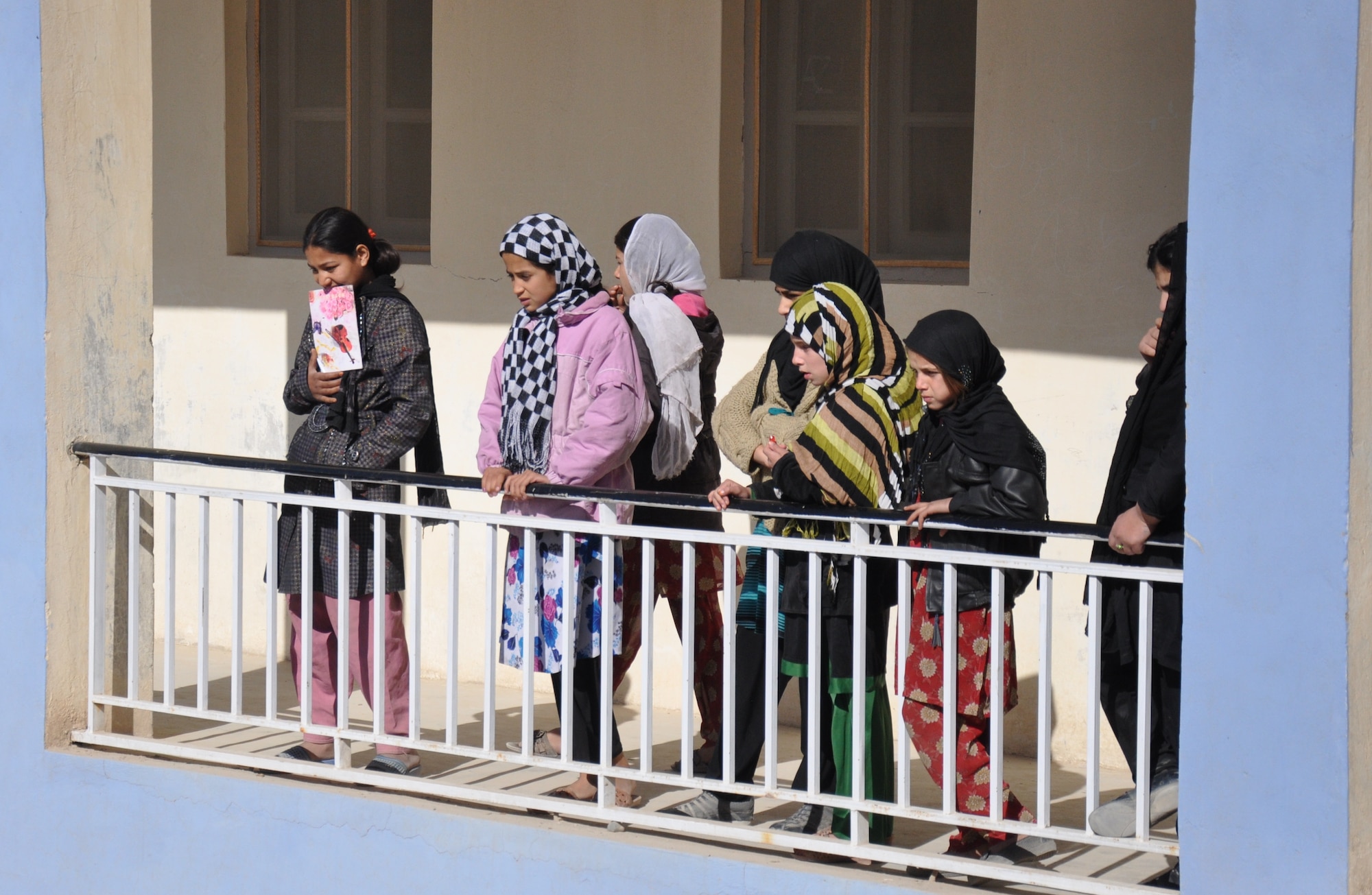 Girls at an Afghan school near Kandahar Airfield look down at the school’s courtyard as Afghan Air Force security forces airmen hand out supplies there on Jan. 24. The mission was led by the Afghans and carried out with logistical and security support from Coalition forces. (U.S. Air Force photo/Capt. Tristan Hinderliter)