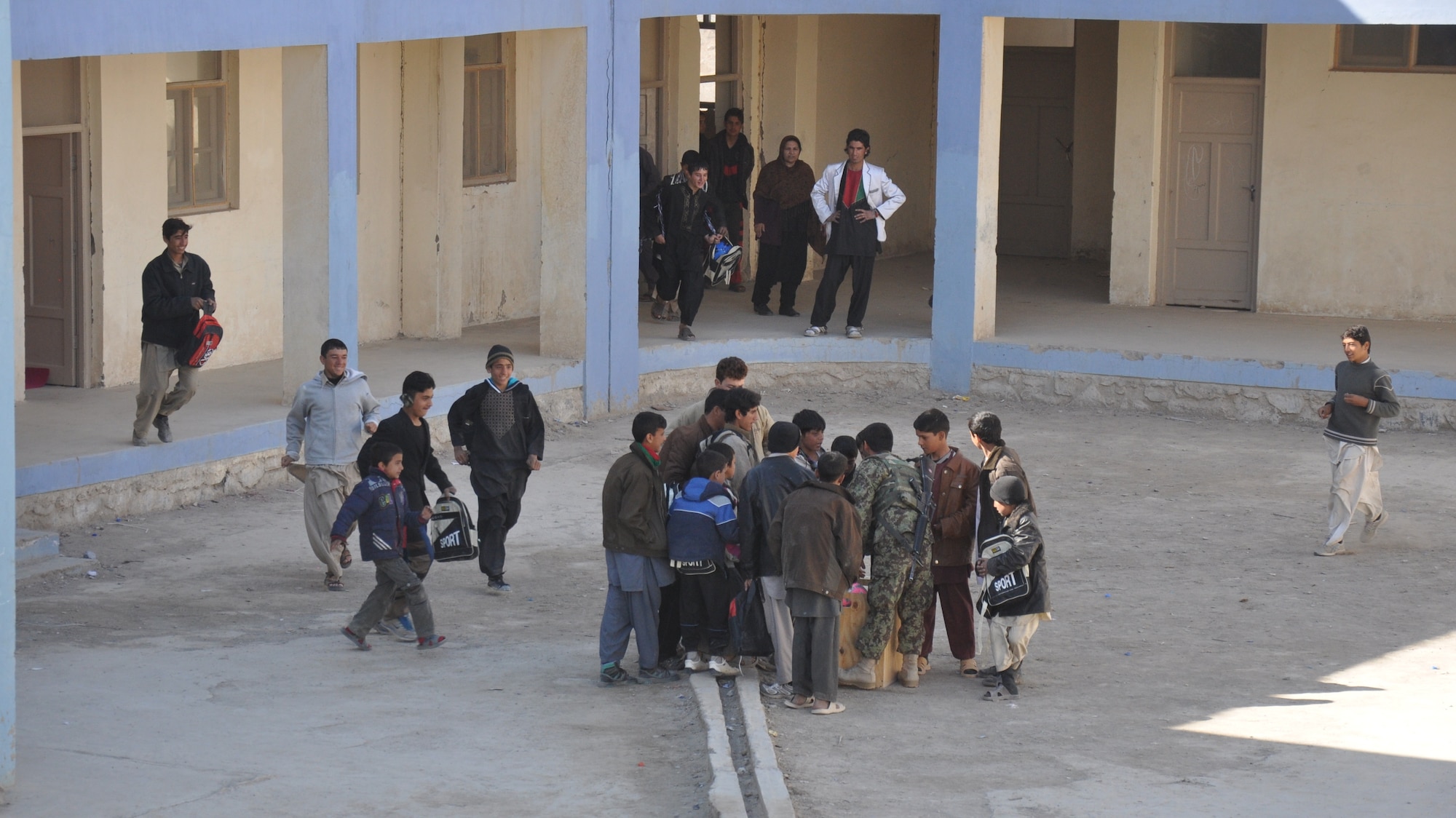 An Afghan security forces airman hands out supplies at a school near Kandahar Airfield on Jan. 24. The mission was led by the Afghans and carried out with logistical and security support from Coalition forces. (U.S. Air Force photo/Capt. Tristan Hinderliter)