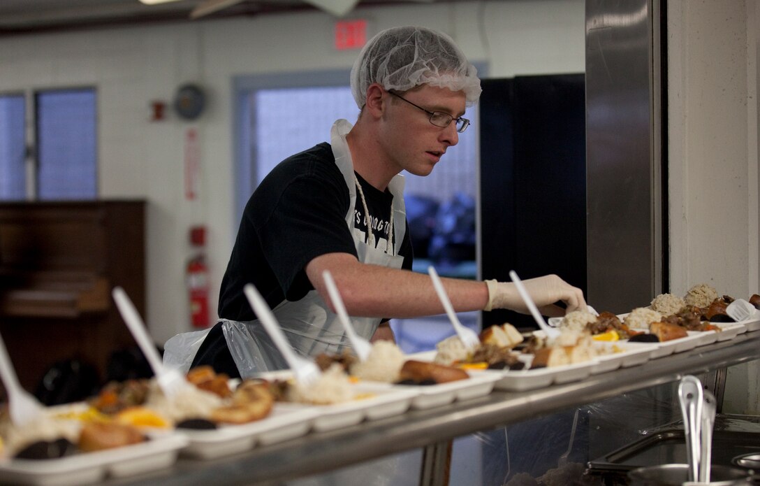 HONOLULU — Seaman Recruit Cameron Wheeler, an air traffic controller with Marine Corps Air Station Kaneohe Bay and native of Vancouver, Wash., places utensils on more than 280 homecooked meals made by Marines, sailors and civilian volunteers from the Marine Corps Base Hawaii community at the Institute of Human Services, Jan. 19. (U.S. Marine Corps photo by Lance Cpl. Jacob D. Barber)