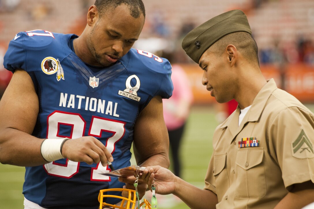 Washington Redskins linebacker Lorenzo Alexander signs an autograph for Cpl. Charles Vallero, a military policeman with Marine Corps Base Hawaii’s Provost Marshal’s Office, after the 2013 NFL Pro Bowl at Aloha Stadium, Jan. 27. Alexander signed many autographs and posed for pictures with the troops after the game, and he even gave out his email to the troops so they could drop him a line. 