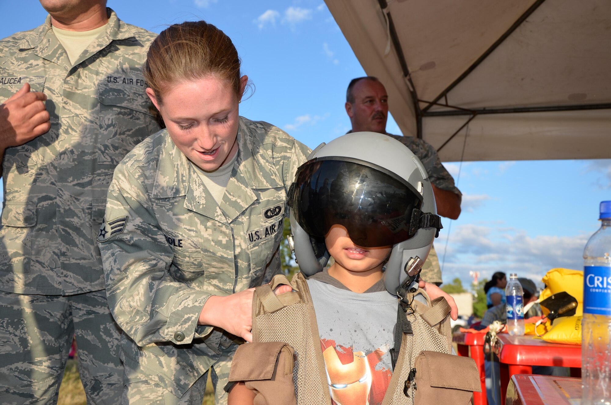 U.S. Air Force Senior Airman Beverly Cole assists a Salvadoran child wearing an aircrew flight helmet and vest at the 2013 Ilopango Air Show in Ilopango, El Salvador as part of a community relations event for the State Partnership Program January 26, 2013.  (N.H. National Guard photo by 1st Lt. Aaron McCarthy/RELEASED)