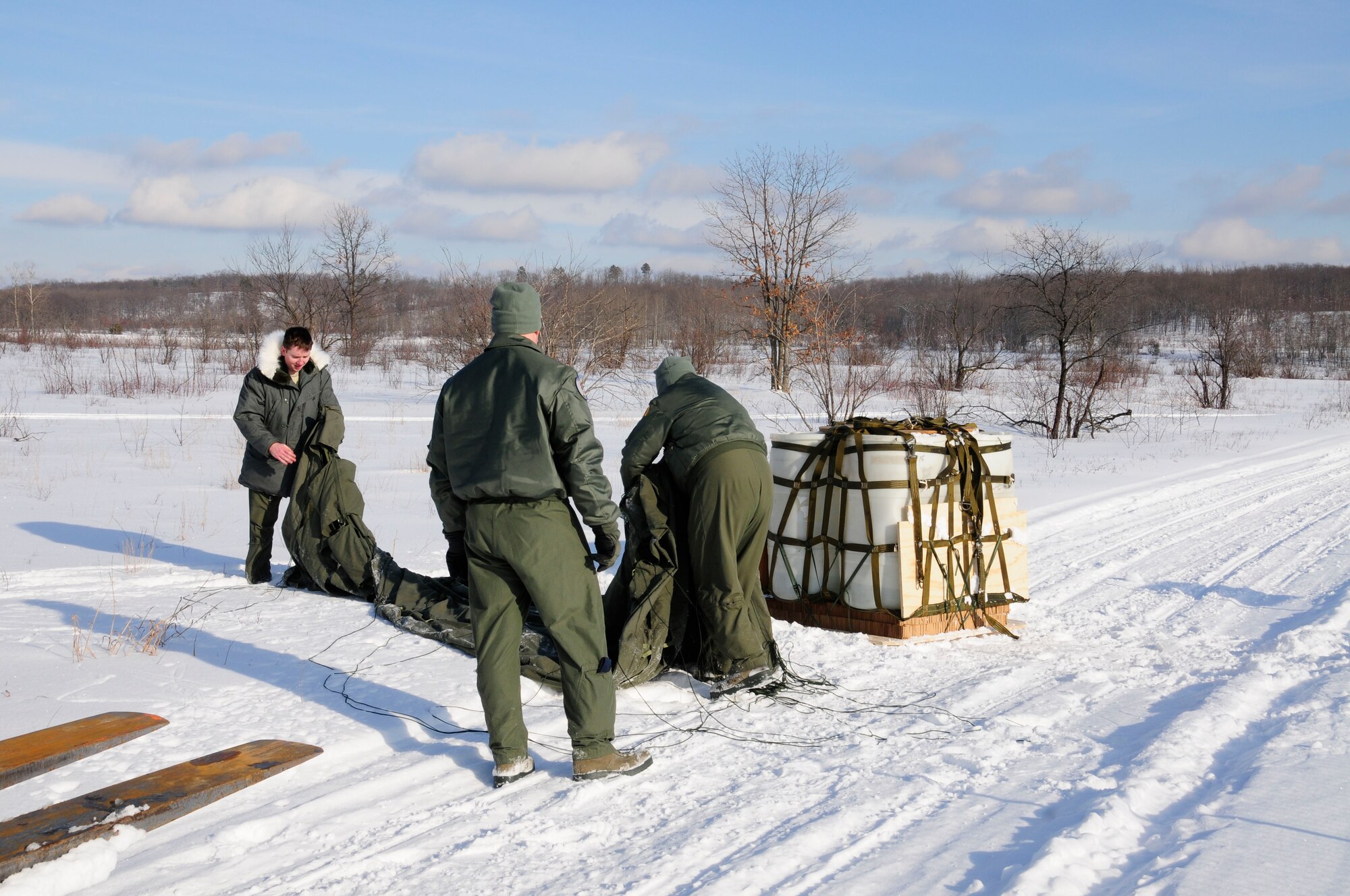 U.S. Air Force Tech. Sgt. Patrick Hann, left, Staff Sgt’s James Benham (center) and Joseph Campbell (right), 110th Airlift Wing, 172nd Airlift Squadron recover a cargo drop from C-130’s, Grayling Air Gunnery Range, Frederic, Mich., Jan. 26, 2013. Cargo was dropped to certify the range and personnel in ground recovery. (U.S. Air Force photo by Airman Justin Andras/released)