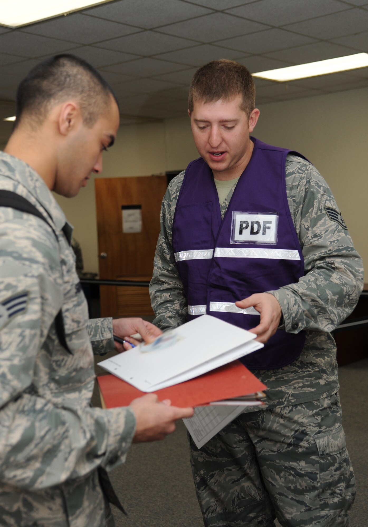 Senior Airman Atif Siddiqui, 81st Security Forces Squadron, gives his medical records folder to Staff Sgt. Joseph Stewart, 81st Aerospace Medicine Squadron, as he goes through the deployment eligibility line during a humanitarian deployment exercise, Jan. 30, 2013, at the Taylor Logistics Center, Keesler Air Force Base, Miss. The exercise scenario consists of an earthquake in Arkansas with a warning order for a deployment to Little Rock, Ark.  (U.S. Air Force photo by Kemberly Groue)