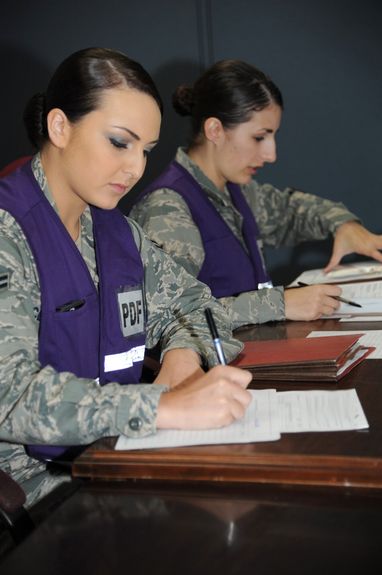 Airman 1st Class Carly Cervantes and Senior Airman Sadie Barcroft, 81st Force Support Squadron, check mobility folders as Airmen process through the deployment eligibility line during a humanitarian deployment exercise, Jan. 30, 2013, at the Taylor Logistics Center, Keesler Air Force Base, Miss.  The exercise scenario consists of an earthquake in Arkansas with a warning order for a deployment to Little Rock, Ark.  (U.S. Air Force photo by Kemberly Groue)
