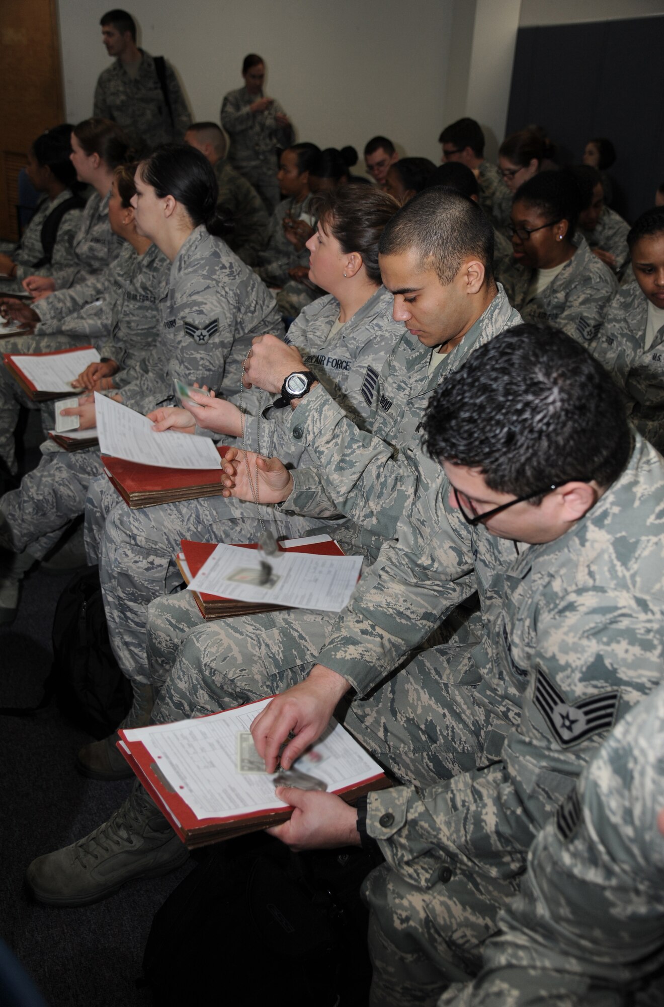 Airmen prepare their mobility records and personal identification information prior to processing through the deployment eligibility line during a humanitarian deployment exercise, Jan. 30, 2013, at the Taylor Logistics Center, Keesler Air Force Base, Miss.  The exercise scenario consists of an earthquake in Arkansas with a warning order for a deployment to Little Rock, Ark.  (U.S. Air Force photo by Kemberly Groue)