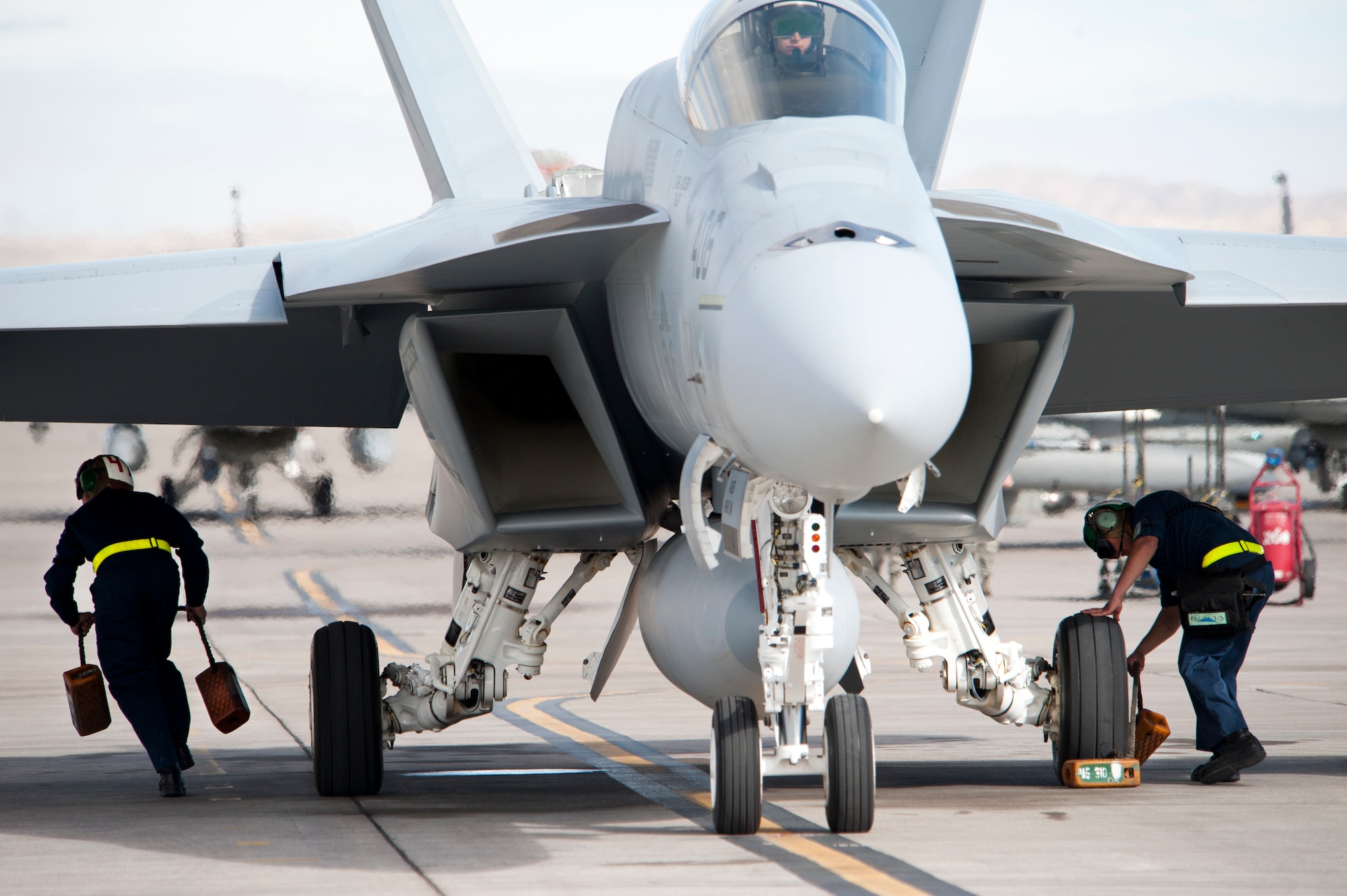 U.S. Navy aircraft maintenance service members assigned to the Strike Fighter Squadron 25 (VFA-25) rapidly remove wheel chalks on an F/A18E Hornet prior to the taxiing onto the Nellis Air Force Base flight line Jan. 25, 2013. The VFA-25 is participating in Red Flag 13-2 to maximize air combat readiness in a realistic training environment. (U.S. Air Force photo by Lawrence Crespo)