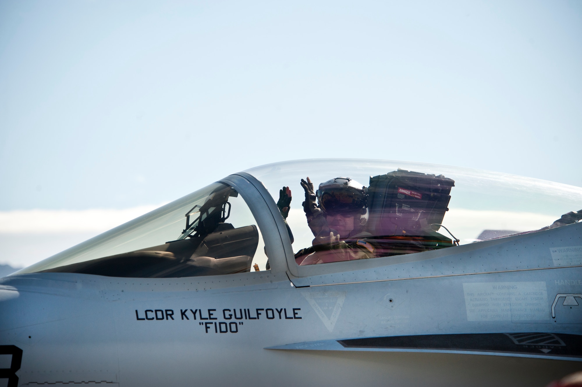 A U.S. Navy F/A-18E Hornet pilot assigned to the Strike Fighter Squadron 25 (VFA-25), Naval Air Station, Lemoore, Calif., signals "all hands off" to a plane captain, during Red Flag 13-2, on the Nellis Air Force Base, Nev. flight line Jan. 25, 2013. The all hands off signal indications aircraft maintenance personnel have control of the aircraft to perform pre-flight operational checks.  (U.S. Air Force photo by Lawrence Crespo)