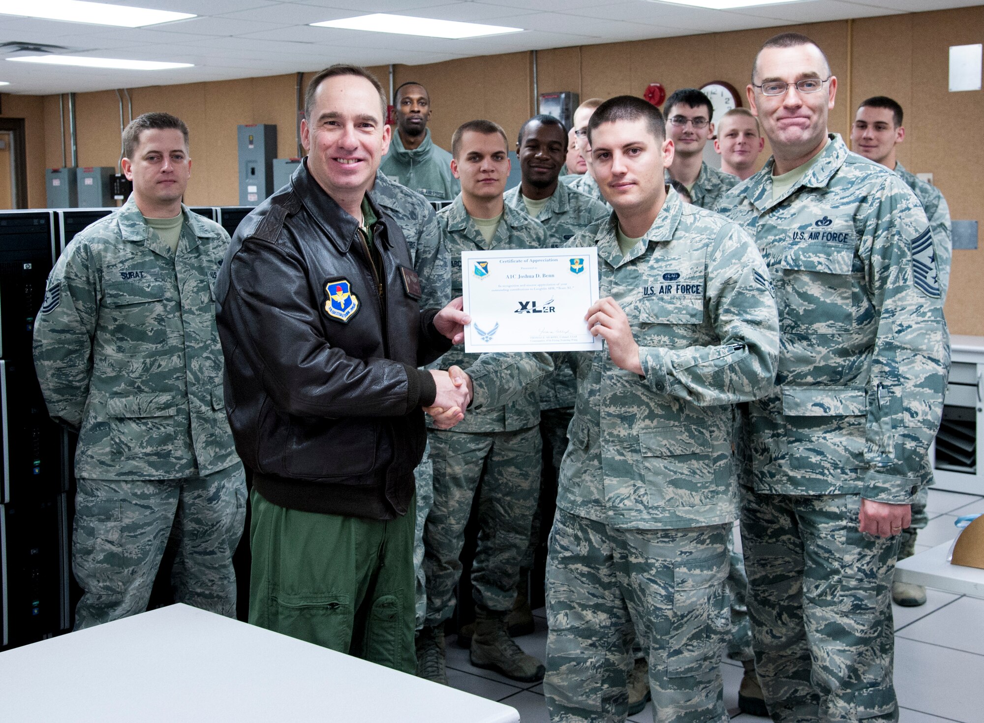 Airman 1st Class Joshua Benn, 47th Communications Squadron client systems technician, poses with Col. Tom Murphy, 47th Flying Training Wing commander, and Chief Master Sgt. Garry Berry, 47th FTW command chief, after being presented the XLer of the week award at Laughlin Air Force Base, Texas, Jan. 17, 2013. The XLer is a weekly award chosen by wing leadership and given to those who consistently make outstanding contributions to Laughlin and their unit. (U.S. Air Force photo/Senior Airman Nathan Maysonet)