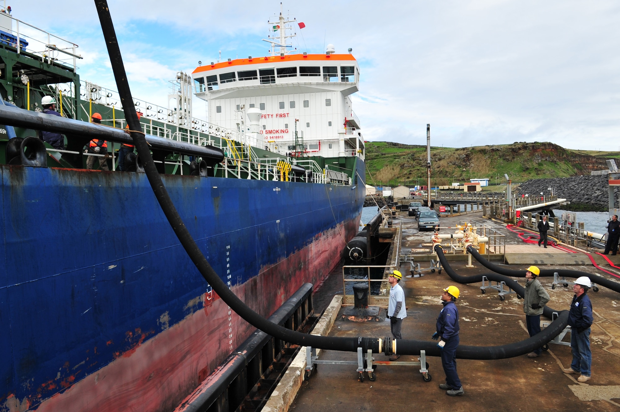 Contractors from Oceanica and AFH Fuels Services, prepare to attach a hose to a fuel tanker at Praia Bay, Azores, Jan. 29.  The fuel tanker delivered 220K gallons of unleaded fuel used to support military and privately owned vehicles.  (U.S. Air Force photo by Tech. Sgt. Chenzira Mallory)