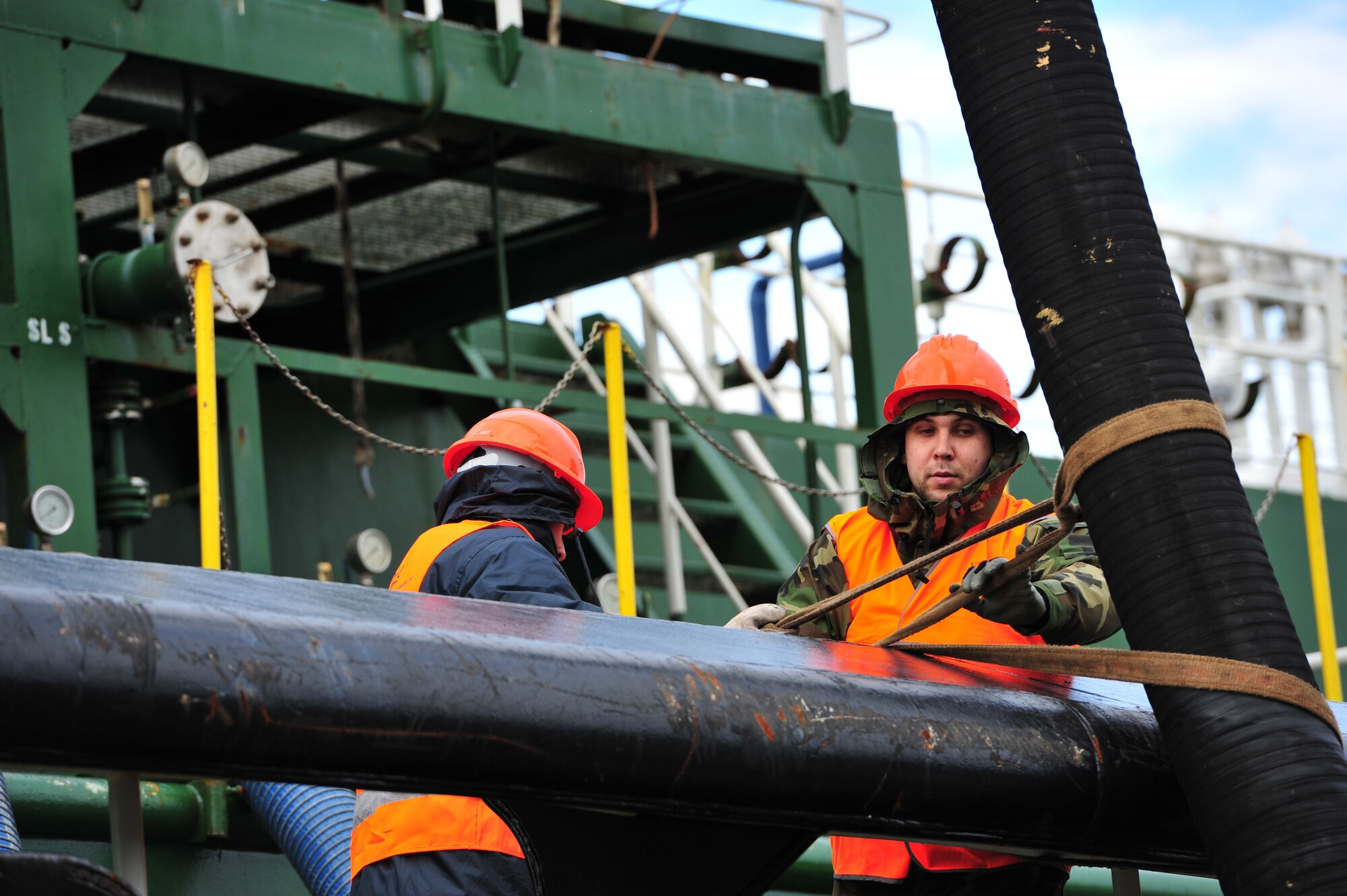 (l-r) Fernando and Leandro Sousa, contractors from Oceanica, prepare to attach a hose to a fuel tanker to offload 200K gallons of unleaded fuel at Praia Bay, Azores, Jan. 29.  Unleaded fuel gets delivered once annually and supports all privately owned vehicles through the Army Air Force Exchange service station.  (U.S. Air Force photo by Tech. Sgt. Chenzira Mallory)