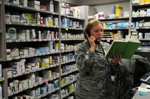 Capt. Christine Cox, 21st Medical Squadron pharmacist and support flight commander, reviews her notes while talking on a phone Jan. 28 at the base pharmacy. The pharmacy's mission is to provide medication services to active-duty members, which include getting them ready to deploy, keeping them healthy. Also, they provide services to dependents and retirees. (U.S. Air Force photo/Staff Sgt. Julius Delos Reyes)