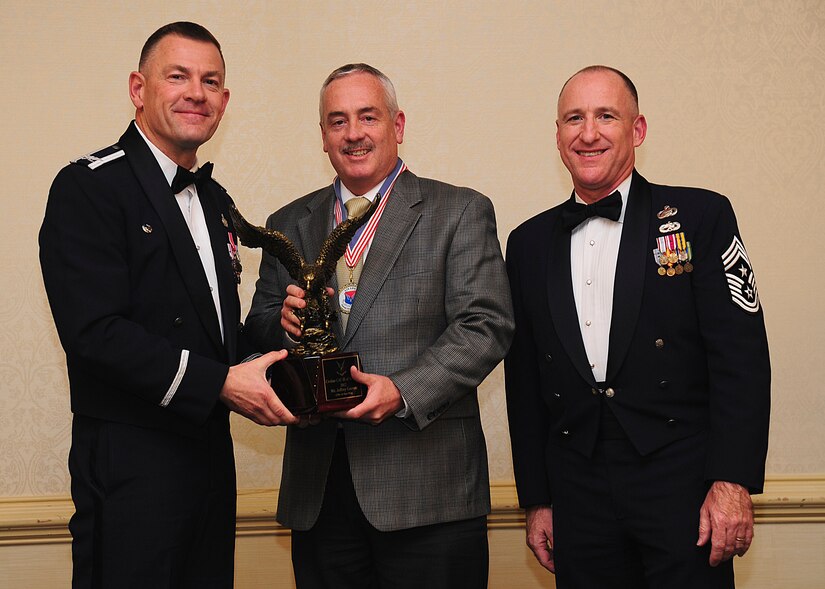 Colonel Richard McComb, Joint Base Charleston commander, and Chief Master Sgt. Al Hannon, 628th Air Base Wing command chief, present the JB Charleston Civilian Category III of the Year award to Jeffrey Garrett, 628th Civil Engineer Squadron chief of asset management flight, during the 628th Air Base Wing Annual Awards Banquet held at the Charleston Club, Jan. 25, 2013, at JB Charleston - Air Base, S.C. (U.S. Air Force photo/Staff Sgt. Rasheen Douglas)