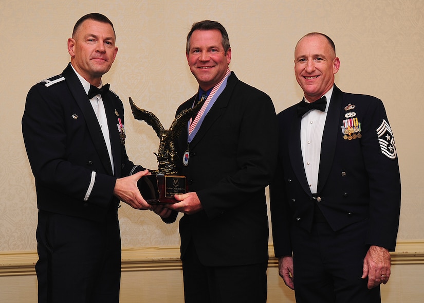 Colonel Richard McComb, Joint Base Charleston commander, and Chief Master Sgt. Al Hannon, 628th Air Base Wing command chief, present the JB Charleston Civilian Category II of the Year award to Michael Heckendorn, 628th Communications Squadron telecommunications project manager, during the 628th ABW Annual Awards Banquet held at the Charleston Club, Jan. 25, 2013, at JB Charleston - Air Base, S.C. (U.S. Air Force photo/Staff Sgt. Rasheen Douglas)