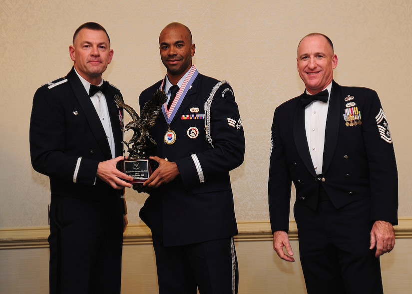 Colonel Richard McComb, Joint Base Charleston commander, and Chief Master Sgt. Al Hannon, 628th Air Base Wing command chief, present the JB Charleston Honor Guard of the Year award to Senior Airman Antonio Hill, 628th Logistics Readiness Squadron vehicle management analysis officer, during the 628th ABW Annual Awards Banquet held at the Charleston Club, Jan. 25, 2013, at JB Charleston - Air Base, S.C. (U.S. Air Force photo/Staff Sgt. Rasheen Douglas)