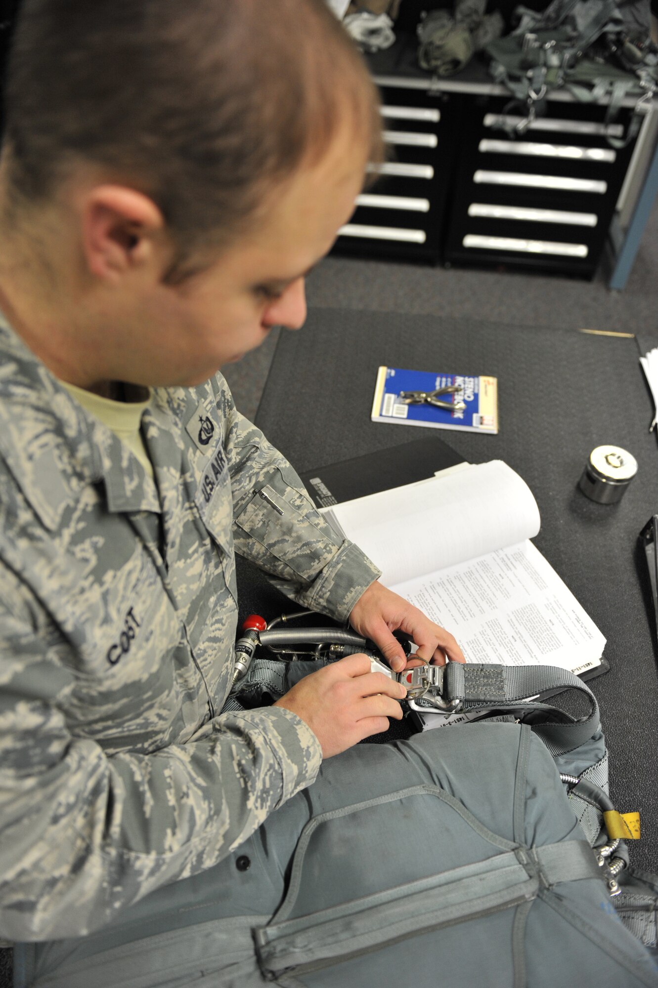 WHITEMAN AIR FORCE BASE, Mo. -- Staff Sgt. Matthew Cost, 509th Operations Support Squadron aircrew flight equipment section lead, uses a technical order as a guide while inspecting aircraft safety equipment during his shift, Jan. 18. Quality assurance sheets are used to assist unit members with preparing safety equipment. (U.S. Air Force photo/Heidi Hunt) (Released)