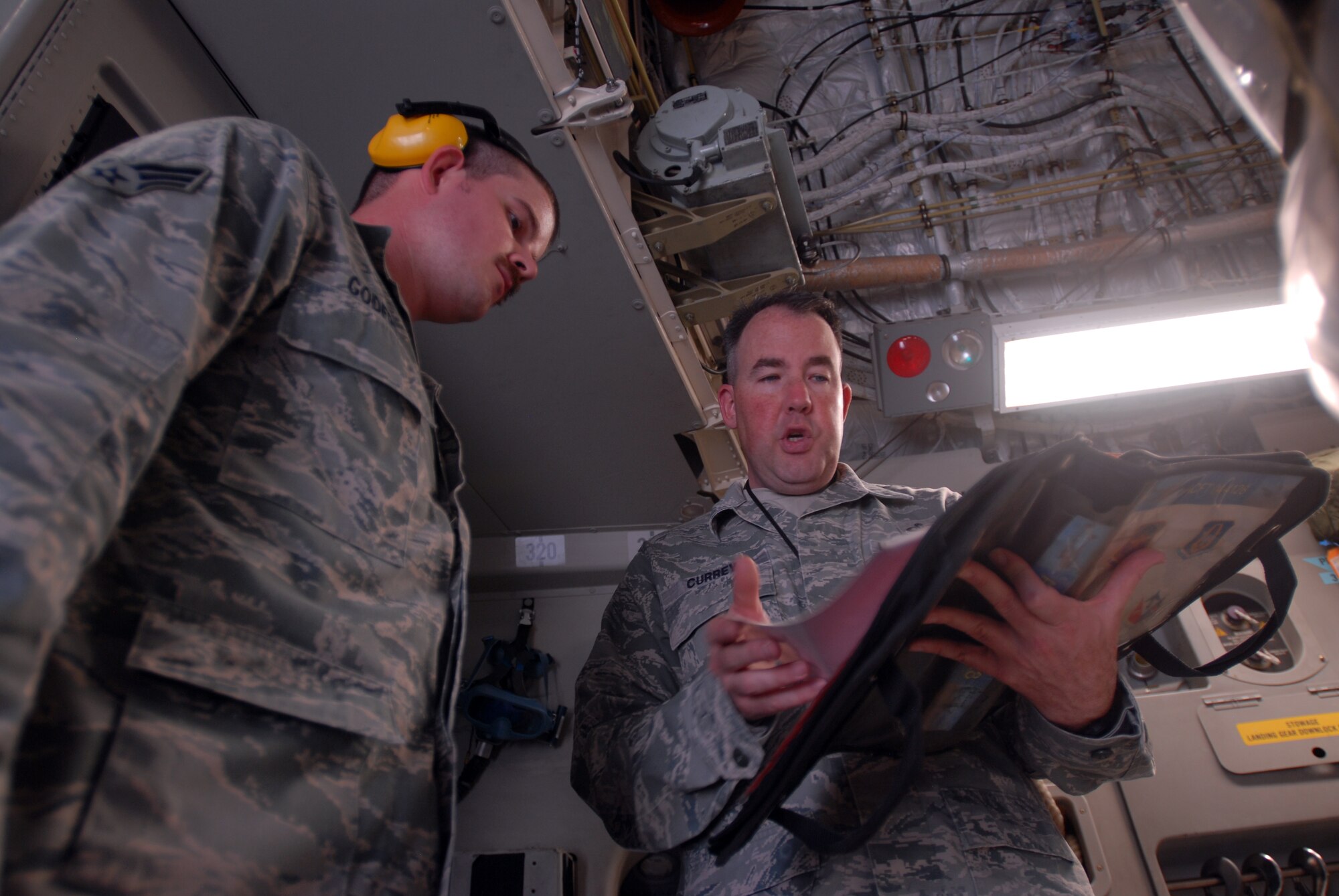 SOUTHWEST ASIA -- Master Sgt. Gregory Currey, shop superintendent, and Senior Airman Daniel Godfrey, Aircrew Flight Equipment lead, inspect C-17A aircraft forms used to track maintenance serviceability of the aircraft. The 816th Expeditionary Airlift Squadron Aircrew Flight Equipment office maintains life-saving equipment for pilots and loadmasters on the C-17A Globemaster III at an undisclosed location Southwest Asia.(U.S. Air Force photo/Master Sgt. Christian Michael)