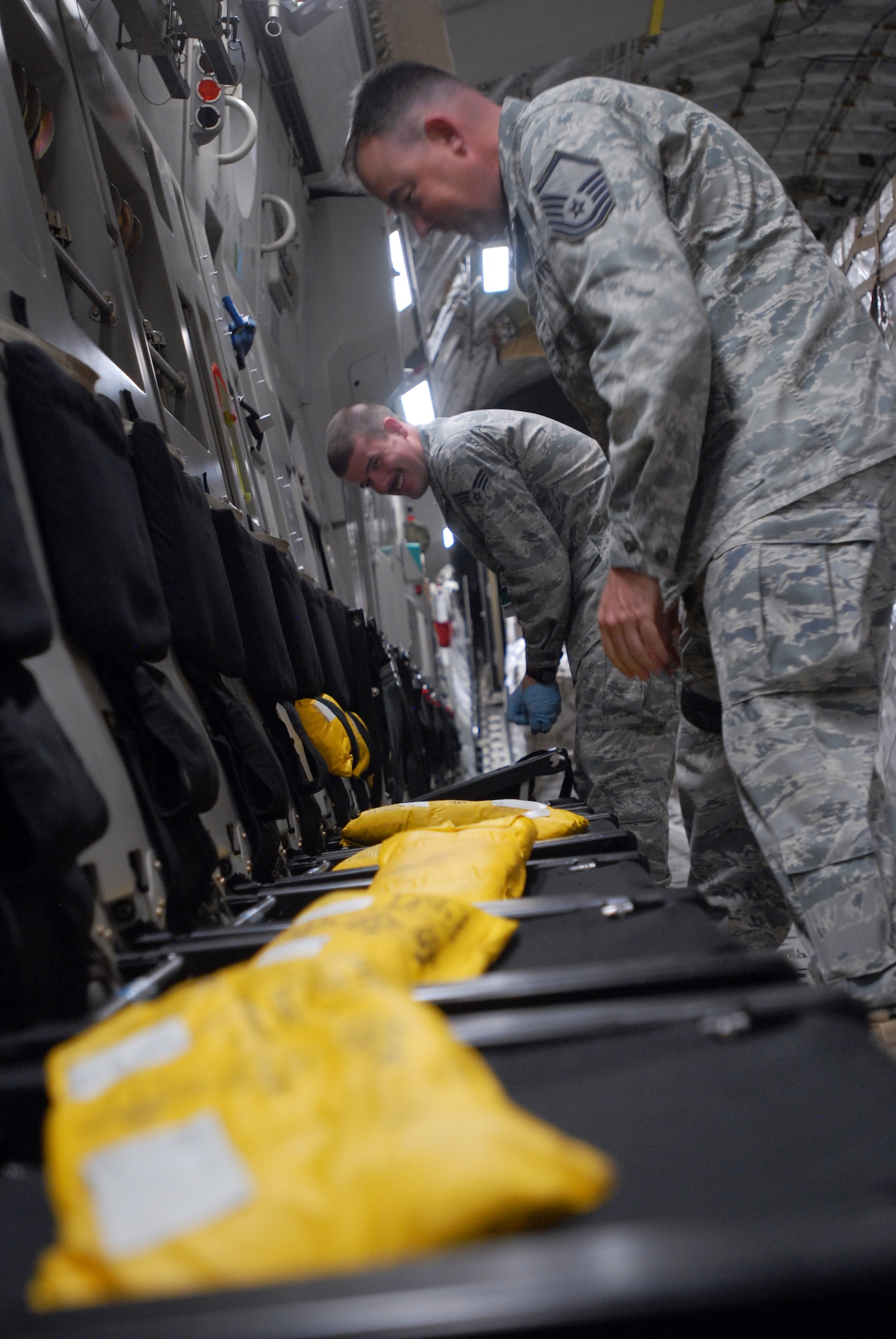 SOUTHWEST ASIA -- Master Sgt. Gregory Currey, shop superintendent, and Senior Airman Daniel Godfrey, Aircrew Flight Equipment lead, conduct a post flight inspection on adult/child life preservers secured within aircraft passengers seats. The 816th Expeditionary Airlift Squadron Aircrew Flight Equipment office maintains life-saving equipment for pilots and loadmasters on the C-17A Globemaster III at an undisclosed location Southwest Asia.(U.S. Air Force photo/Master Sgt. Christian Michael)