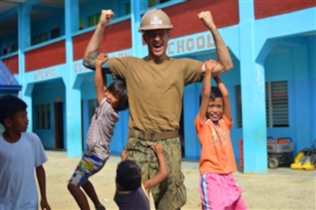 U.S. Navy Seaman Joseph Caruso plays with children in Barangay Tagburos in Puerto Princesa City, Philippines, Jan. 25, 2013. The Seabees assigned to Naval Mobile Construction Battalion 5 make up the construction civic action detail Philippines. 