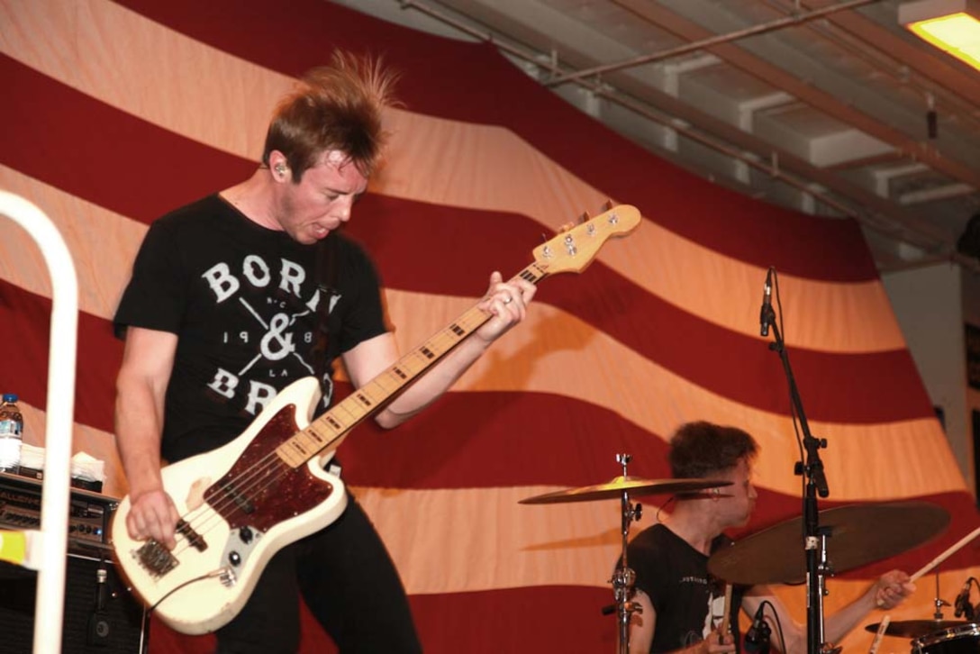 Deon Rexroat, bass player for the band Anberlin, performs for the Marines and sailors of the 15th Marine Expeditionary Unit and Peleliu Amphibious Ready Group during an Anberlin concert held in the hangar bay of the USS Peleliu, Jan. 21. Anberlin, a rock band from the United States, spent more than 20 hours traveling to see the deployed Marines and sailors of the 15th MEU and Peleliu ARG, Jan. 21-22. The visit included a musical performance as well as a tour of the ship and its amenities. The 15th MEU is deployed as part of the Peleliu ARG as a U.S. Central Command theater reserve force, providing support for maritime security operations and theater security cooperation efforts in the U.S. 5th Fleet area of responsibility. (U.S. Marine Corps photo by Cpl. John Robbart III)