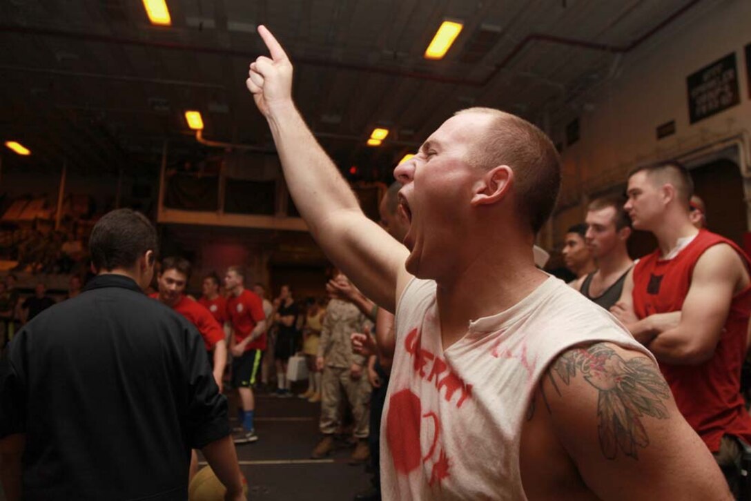 Aviation Ordnanceman 3rd Class Jonathan C. Steen, USS Peleliu, cheers on his teammates during a dodgeball tournament held in the hangar bay of the USS Peleliu, Jan. 24. The dodgeball challenge was the eighth competition of the Campbell Cup, a bi-monthly challenge that pits teams within the 15th Marine Expeditionary Unit and Peleliu ARG against each other. The 15th MEU is deployed as part of the Peleliu Amphibious Ready Group as a U.S. Central Command theater reserve force, providing support for maritime security operations and theater security cooperation efforts in the U.S. 5th Fleet area of responsibility. Steen, 21, is from San Angelo, Texas. (U.S. Marine Corps photo by Cpl. John Robbart III/Released)