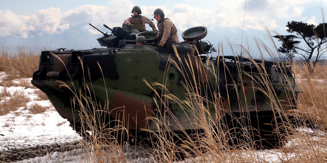 Assault amphibious vehicle crew members instruct Pfc. Nathan E. Craig, center, on how to operate an AAV Jan. 24 in the North Fuji Maneuver Area at Combined Arms Training Center Camp Fuji on mainland Japan. Marines with Combat Assault Battalion provided artillerymen the opportunity to experience the capabilities of AAVs firsthand. Craig is a motor transport operator with 3rd Battalion, 12th Marine Regiment, 3rd Marine Division, III Marine Expeditionary Force. The AAV crew members are with CAB, 3rd Marine Division. 