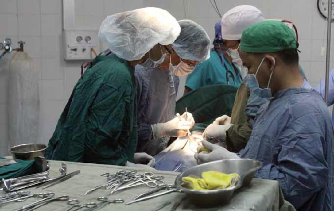 U.S. Navy Lt. Kim Nguyen, left, observes as Royal Cambodian Armed Forces surgeons operate on a patient Jan. 24 at the Phnom Penh Preah Ket Melea Hospital in Phnom Penh, Cambodia, during Cambodia Medical Exercise 13-1. “It’s inspiring to see the doctors overcome the challenges they face every day,” said Nguyen. “They are aware they are sometimes short on resources, but modify their care and techniques for the good of patients.” The U.S. service members are working alongside Royal Cambodian Armed Forces medical personnel during subject-matter expert exchanges to increase Cambodia and
U.S. medical capability, capacity and interoperability. Nguyen is a general surgeon with 3rd Medical Battalion, Combat
Logistics Regiment 35, 3rd Marine Logistics Group, III Marine Expeditionary Force. Photo by 