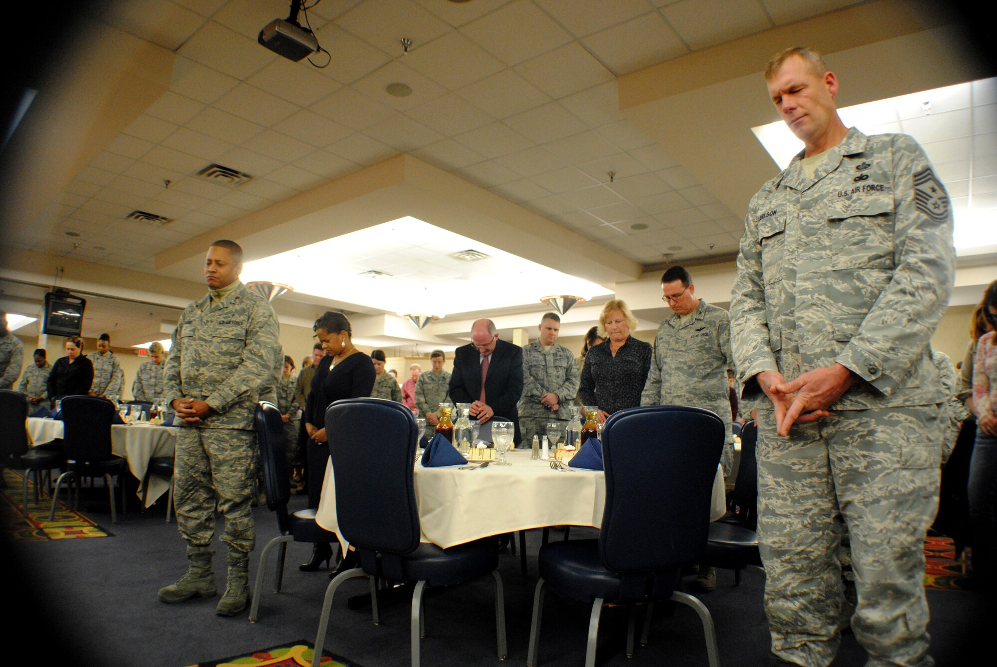 With bowed heads, guests stand silently while Chaplain (Maj.) Craig Benson leads a prayer during the National Prayer Luncheon hosted by the 319th Air Base Wing Chaplain Office Jan. 30, 2013, at the Northern Lights Club on Grand Forks Air Force Base, N.D.  (U.S. Air Force photo/Senior Airman Luis Loza Gutierrez)