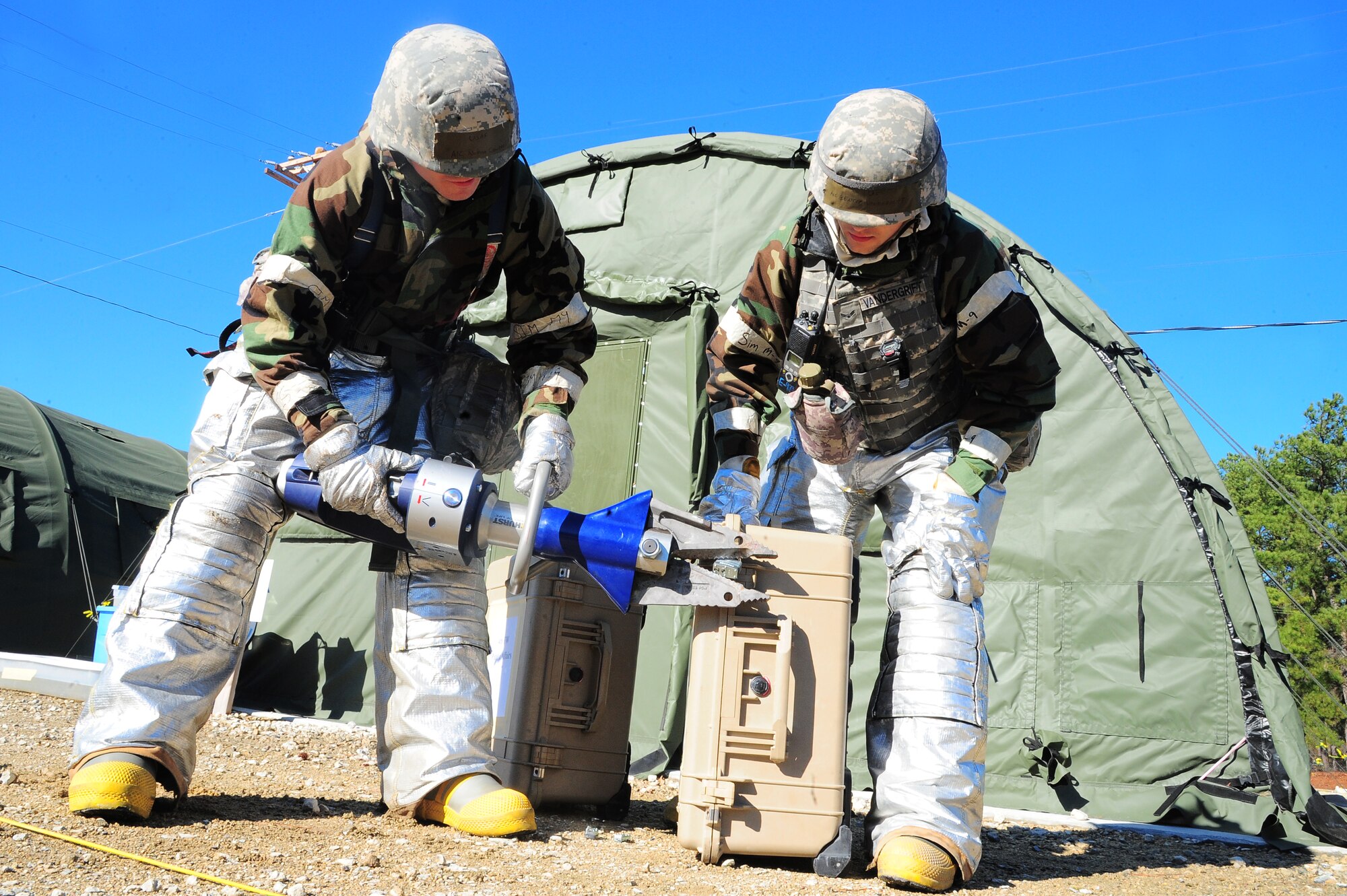 U.S. Air Force Airman 1st Class Nathan Cowper, 4th Civil Engineer Squadron firefighter, removes a lock as Airman 1st Class Benton Vandergrift looks on during Operational Readiness Exercise Coronet Warrior 13-01B, at a simulated deployed location on Seymour Johnson Air Force Base, N.C., Jan. 31, 2013. A photojournalist assigned to the 4th Fighter Wing Public Affairs office lost the keys to their computer cases and sought assistance from their firefighter wingmen.(U.S. Air Force photo/Airman 1st Class Aubrey White/ Released)