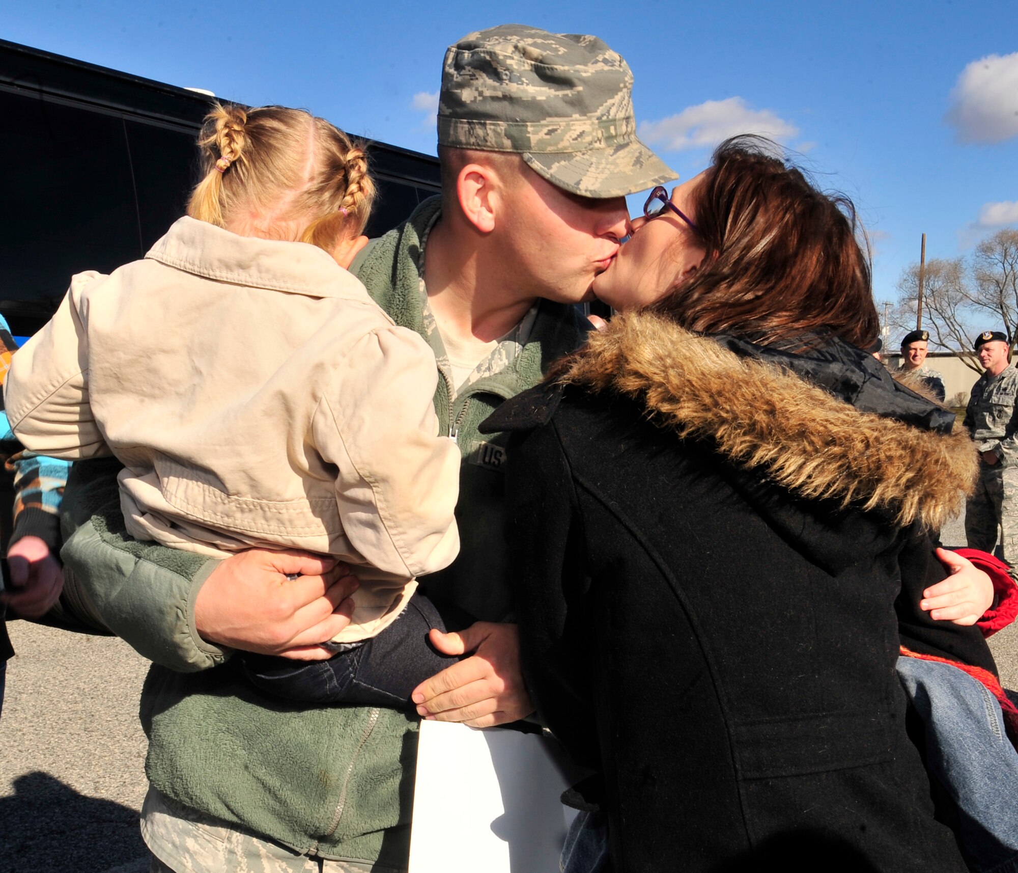 Staff Sgt. Jeffery Holub, 436th Security Forces Squadron, kisses his wife Tracy and holds his daughter Peyton Jan. 13, 2013, at the 436th SFS building on Dover Air Force Base, Del. Holub and two teams of 436th SFS members returned from a six-month deployment to Southwest Asia. (U.S. Air Force photo by Tech. Sgt. Chuck Walker)