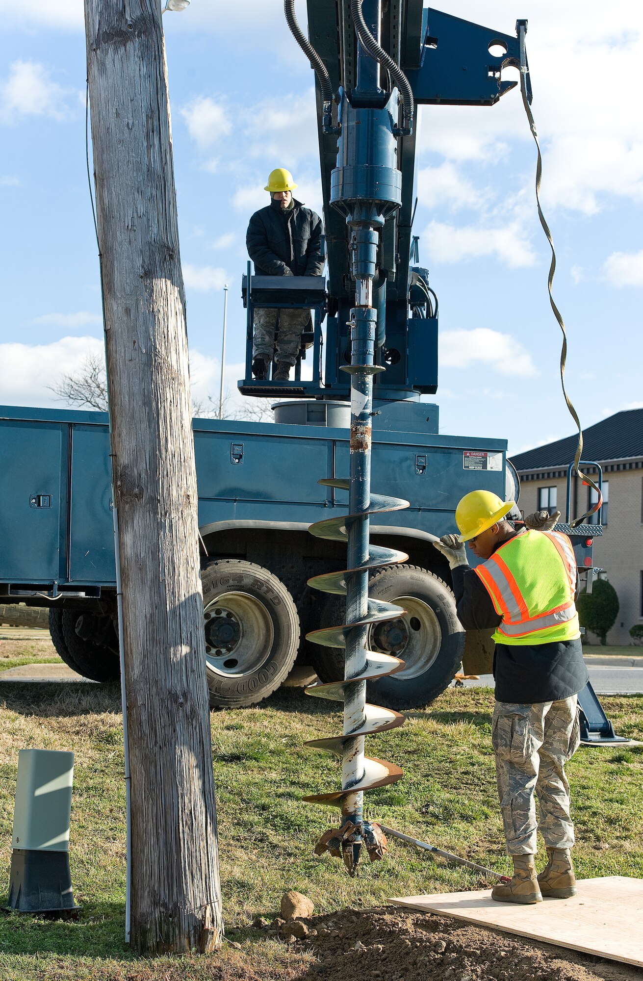 Tech. Sgt. Brian Robinson, right, and Staff Sgt. Leopoldo Galindo, both of the 436th Civil Engineer Squadron, Electric Shop, position a line truck auger Jan. 31, 2013, at Dover Air Force Base, Del. A seven-foot hole was dug for a temporary support pole which was secured to a broken pole caused by high winds. (U.S. Air Force photo/Roland Balik)
