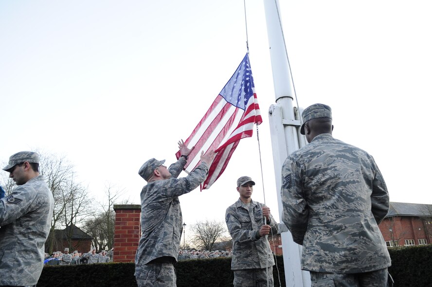 Team Mildenhall honor guardsmen retrieve a U.S. flag as it is lowered during a retreat ceremony Jan. 30, 2013, at RAF Mildenhall, England. Airmen from multiple squadrons participated in the ceremony to honor Chief Master Sgt. Christopher Powell, 100th Air Refueling Wing command chief’s, upcoming retirement. (U.S. Air Force photo by Airman 1st Class Dillon Johnston/Released)